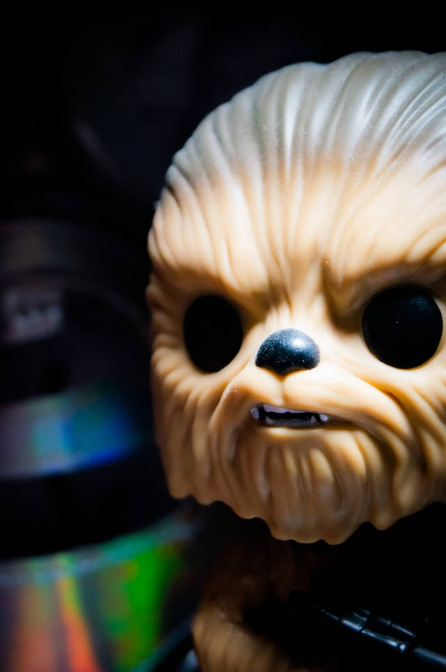 星際大戰 iPhone 桌布 壁紙 — 特寫鏡頭：Funko Pop Chewbacca 人偶，眼睛發光，毛髮有紋理，背景黑暗。