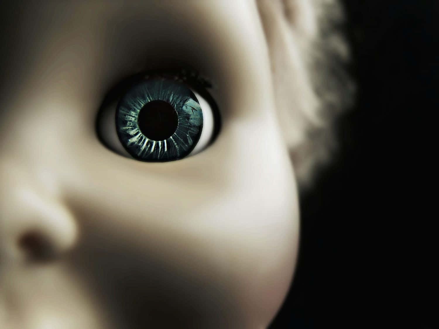 Doll 桌布 壁紙 — 特寫鏡頭，一個洋娃娃令人毛骨悚然的藍色眼睛，細節豐富，背景黑暗。