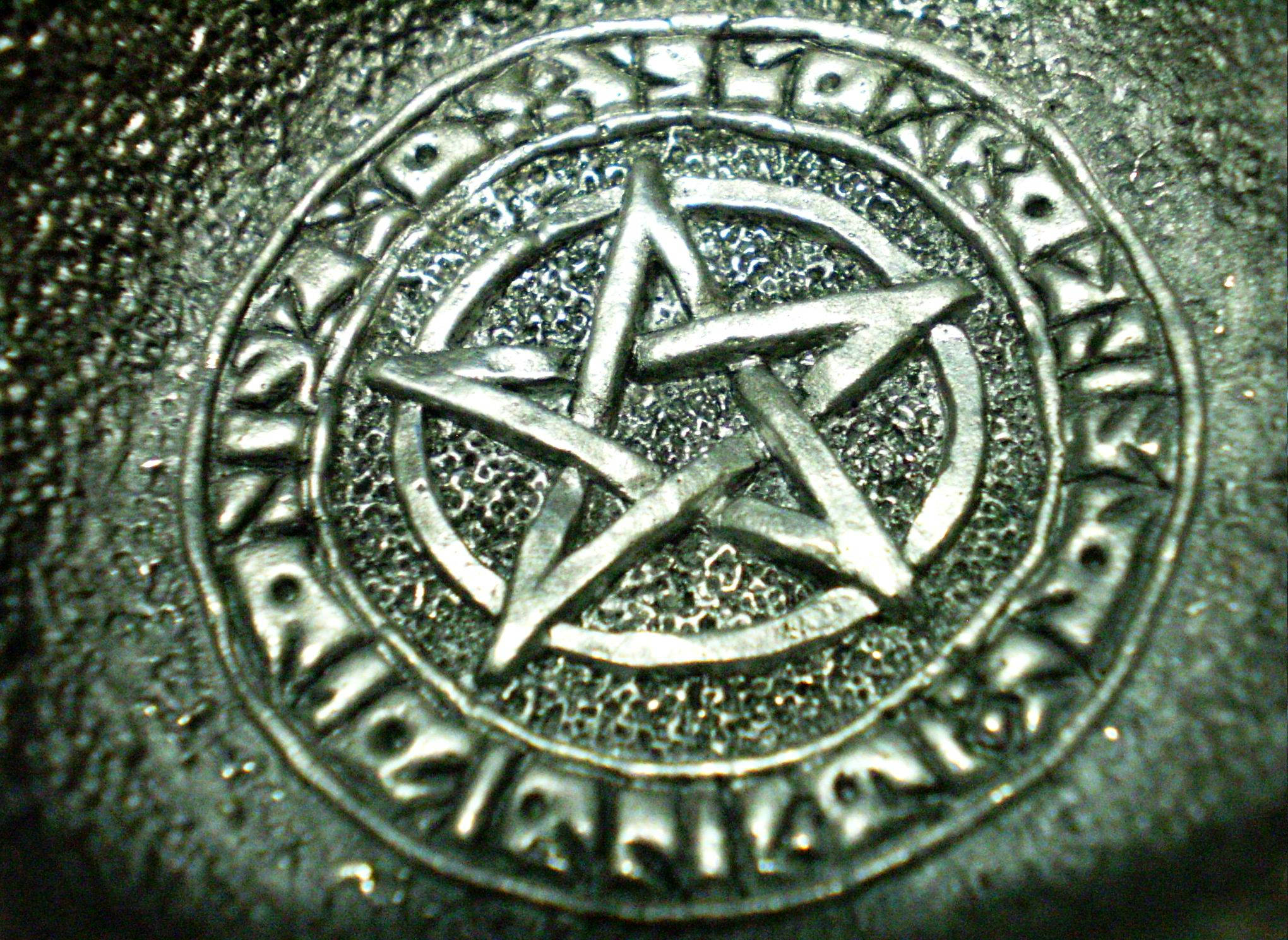 Stone 桌布 壁紙 — 特寫鏡頭：一個金屬五角星符號，刻在一個由古代符文組成的圓形邊框內，位於紋理表面上。