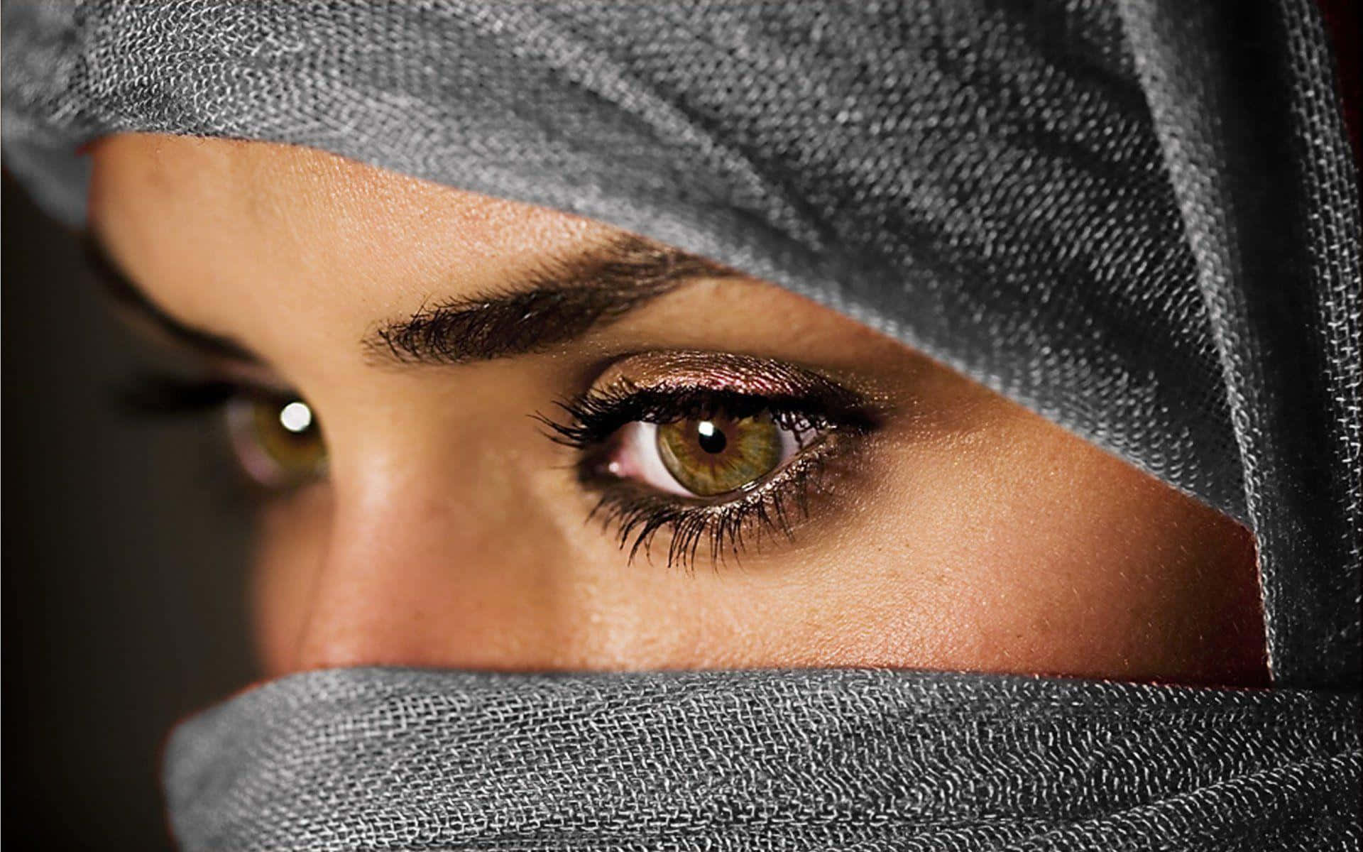 Eyes 桌布 壁紙 — 特寫鏡頭：一名女性透過質感灰色尼卡布窺視，露出帶有戲劇性妝容的強烈綠色眼睛。