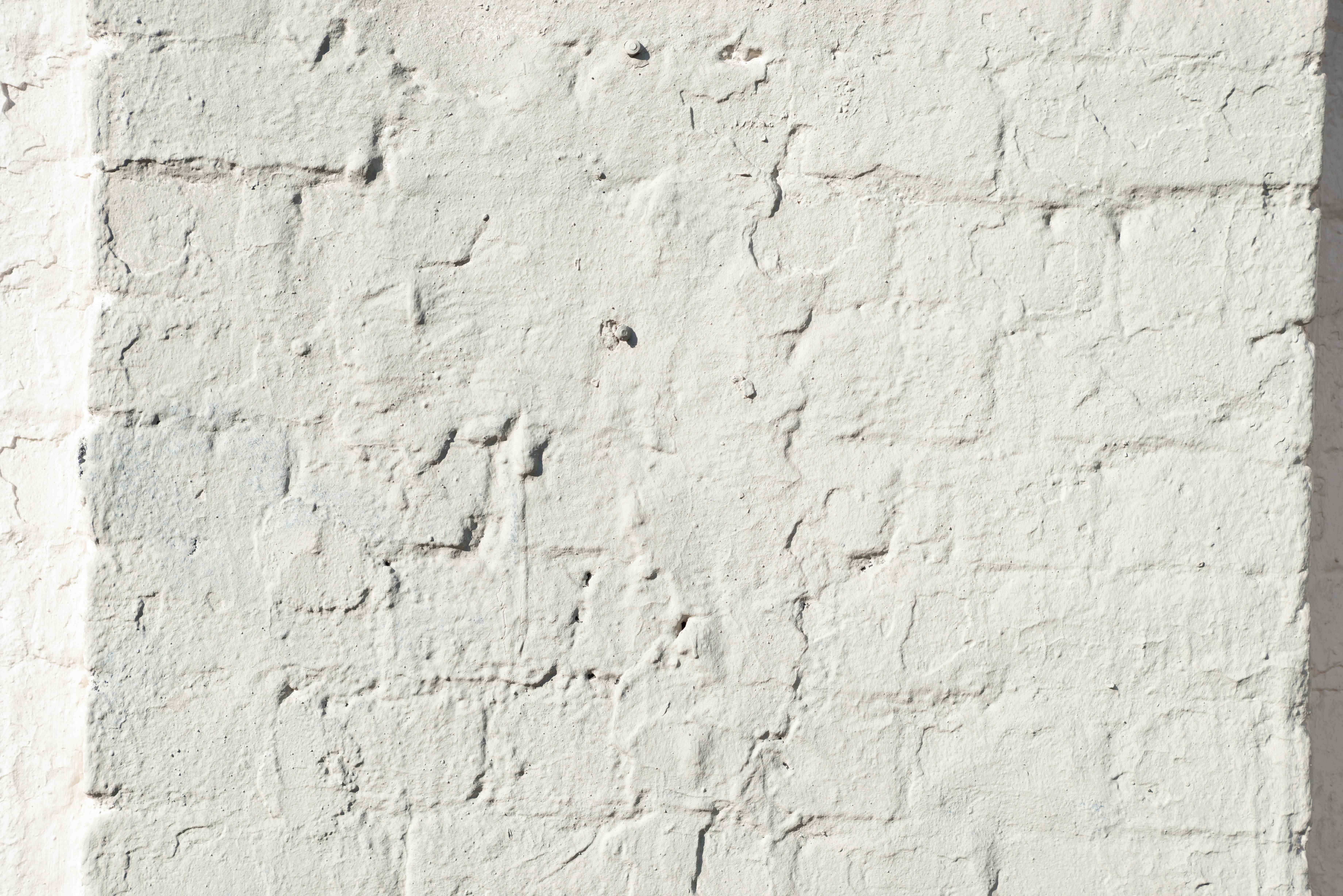 White Brick Wall 桌布 壁紙 — 特寫鏡頭：一堵經風化的白色磚牆，在明亮光線下呈現紋理和細微裂縫。