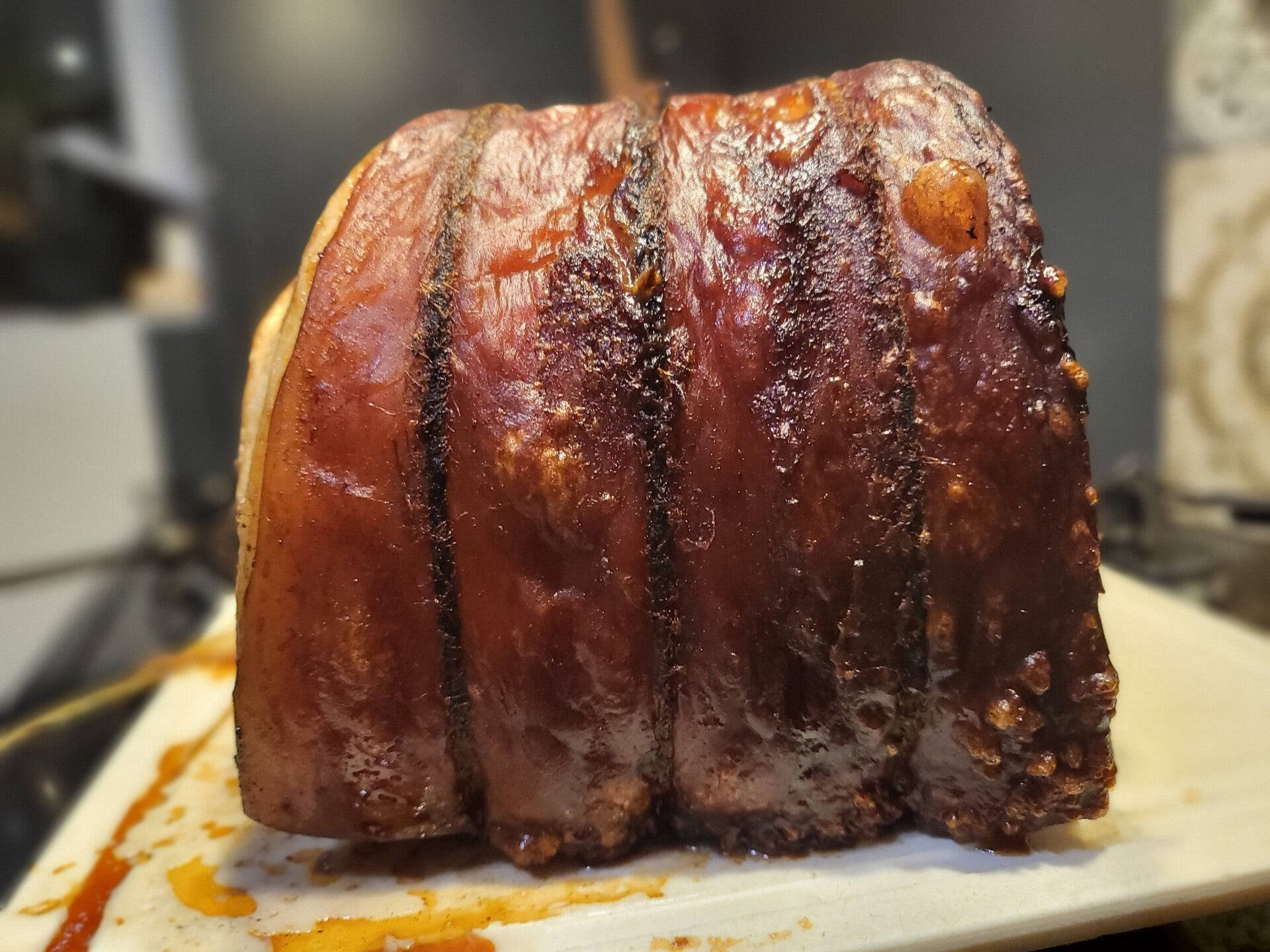 Pig 桌布 壁紙 — 特寫鏡頭：一塊木砧板上的烤豬肩肉，帶有焦糖化外皮和多汁質感，表面有光澤的釉面。