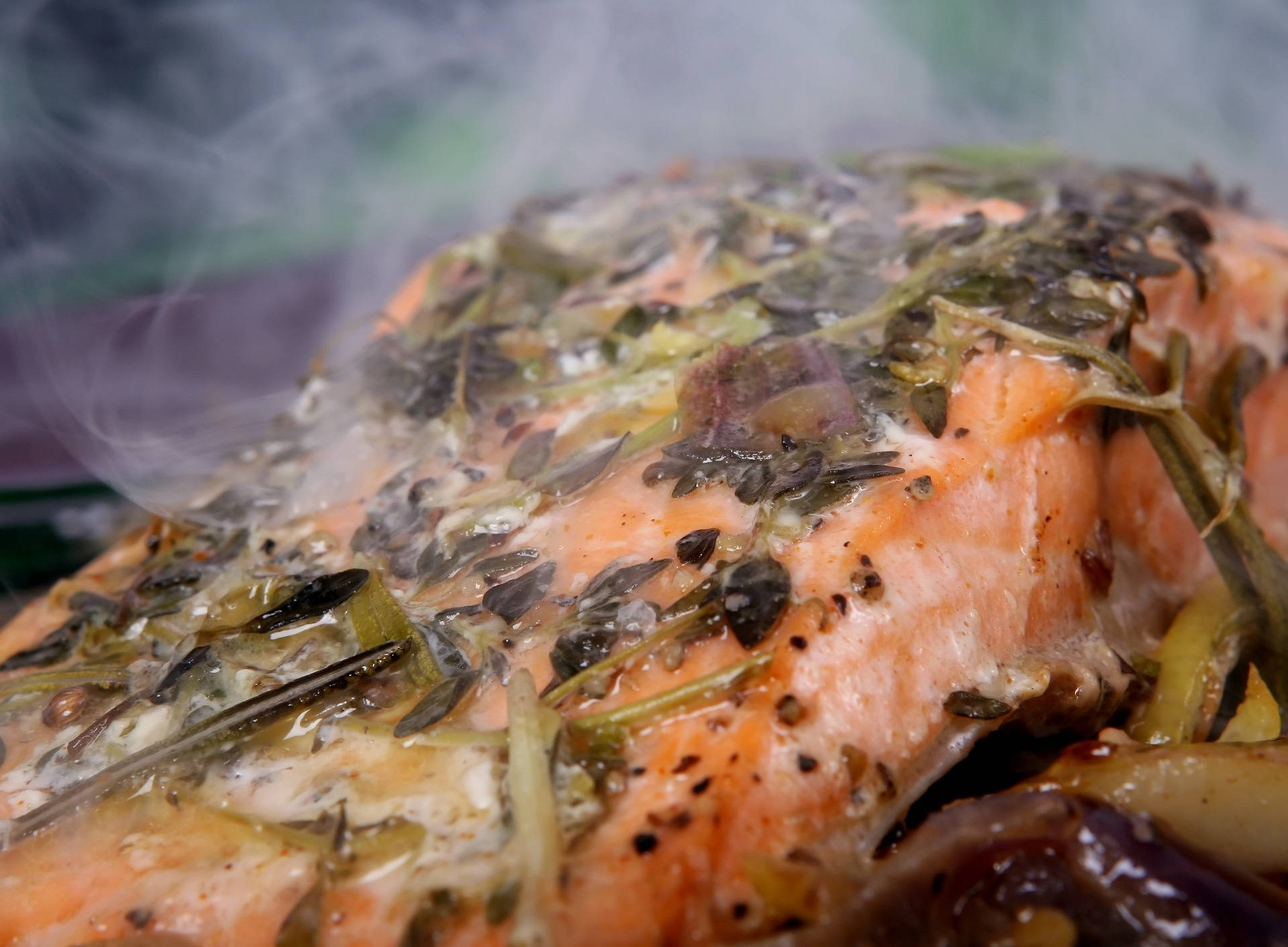 yummy 桌布 壁紙 — 特寫鏡頭：一塊蒸鮭魚片，上面鋪滿香草和香料，散發出芳香煙霧。
