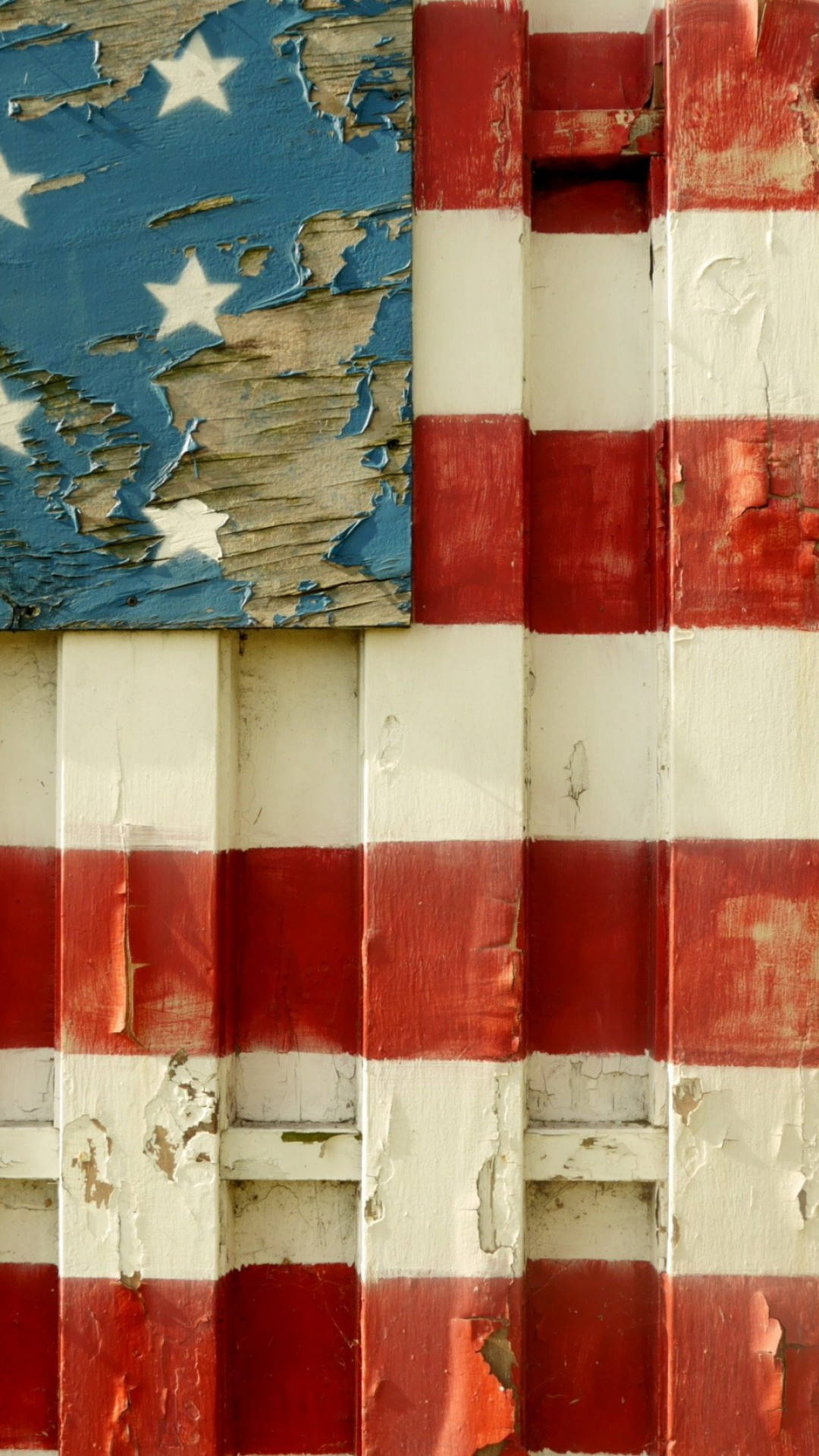 USA flag iPhone 桌布 壁紙 — 特寫鏡頭：一幅繪在木板上、經風化的美國國旗，紅色、白色和藍色油漆剝落，露出底下的舊木。
