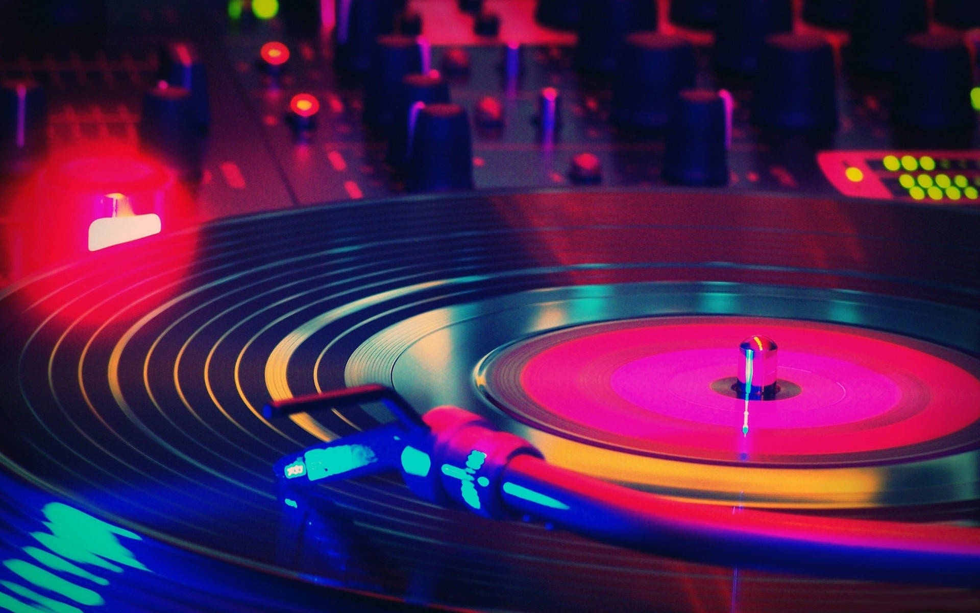 DJ 桌布 壁紙 — 特寫鏡頭：一張旋轉的黑膠唱片在DJ唱盤上，沐浴在鮮豔的霓虹紅、藍和綠光中。