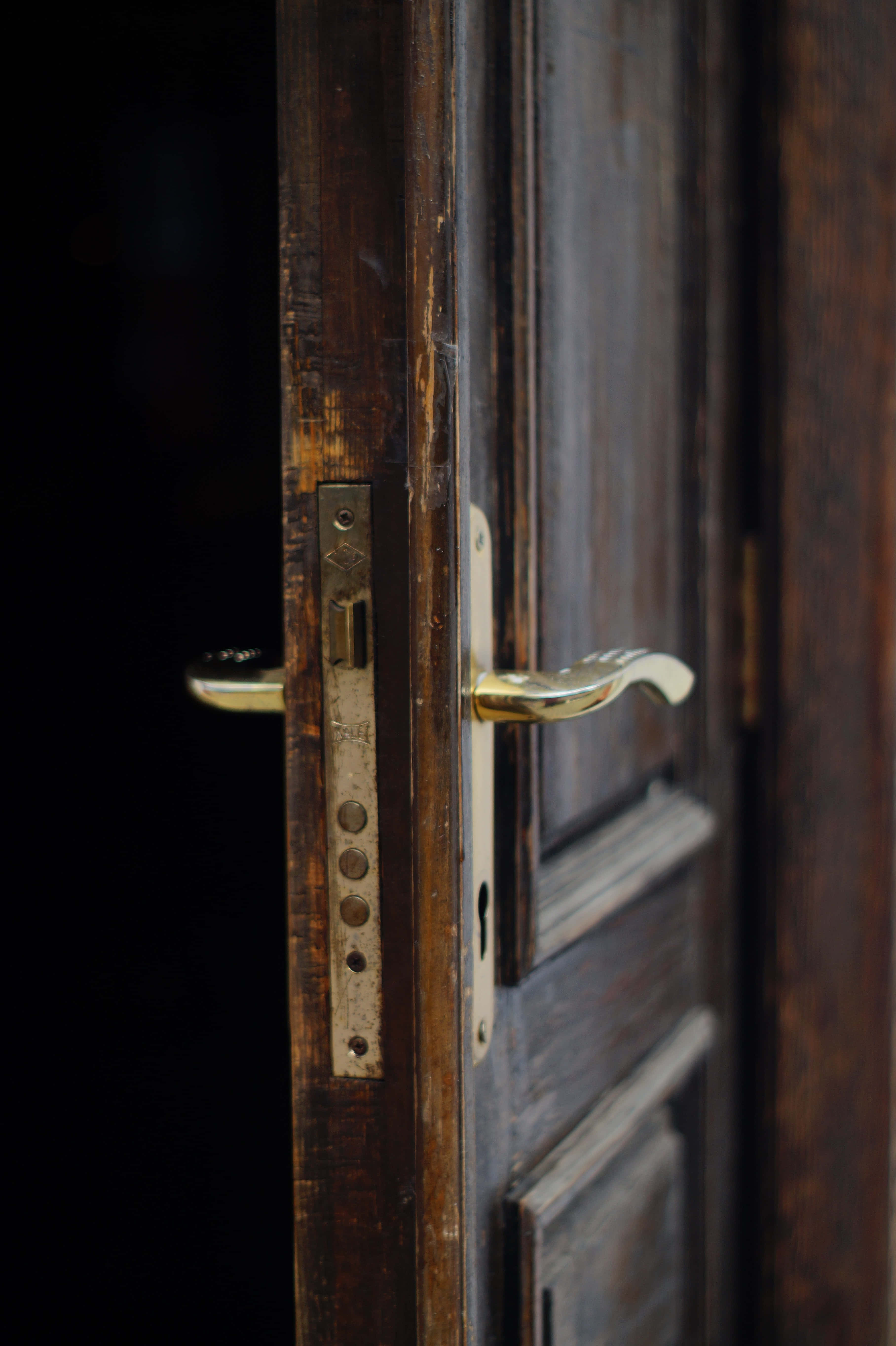 Door 桌布 壁紙 — 特寫鏡頭：一扇歷經風霜的木門，配有黃銅把手和復古鎖，背景為深色。