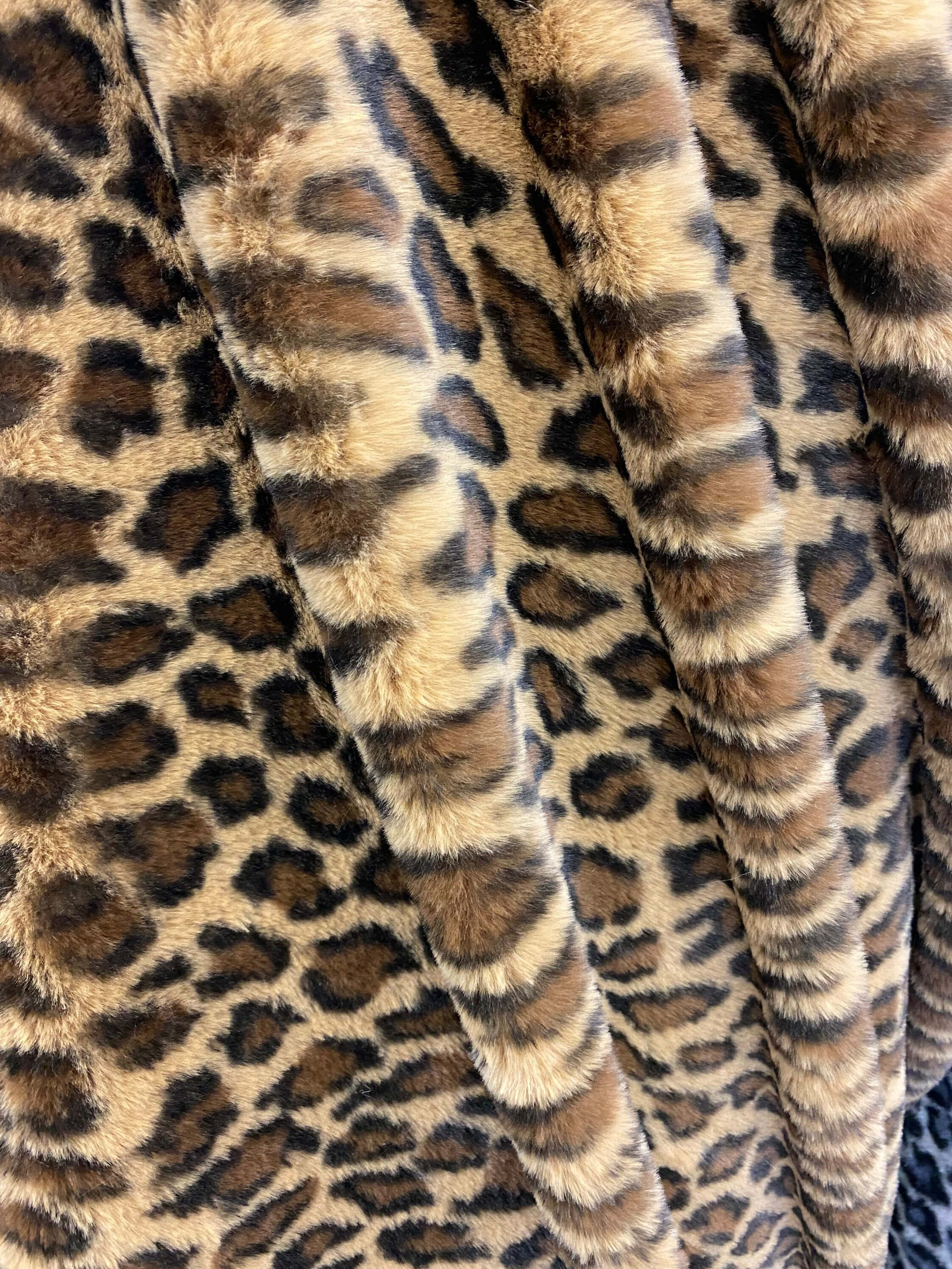 Animal Fur 桌布 壁紙 — 特寫鏡頭：一條豪華人造毛皮毯子，帶有大膽的豹紋圖案，色調為濃郁的棕色和棕褐色。
