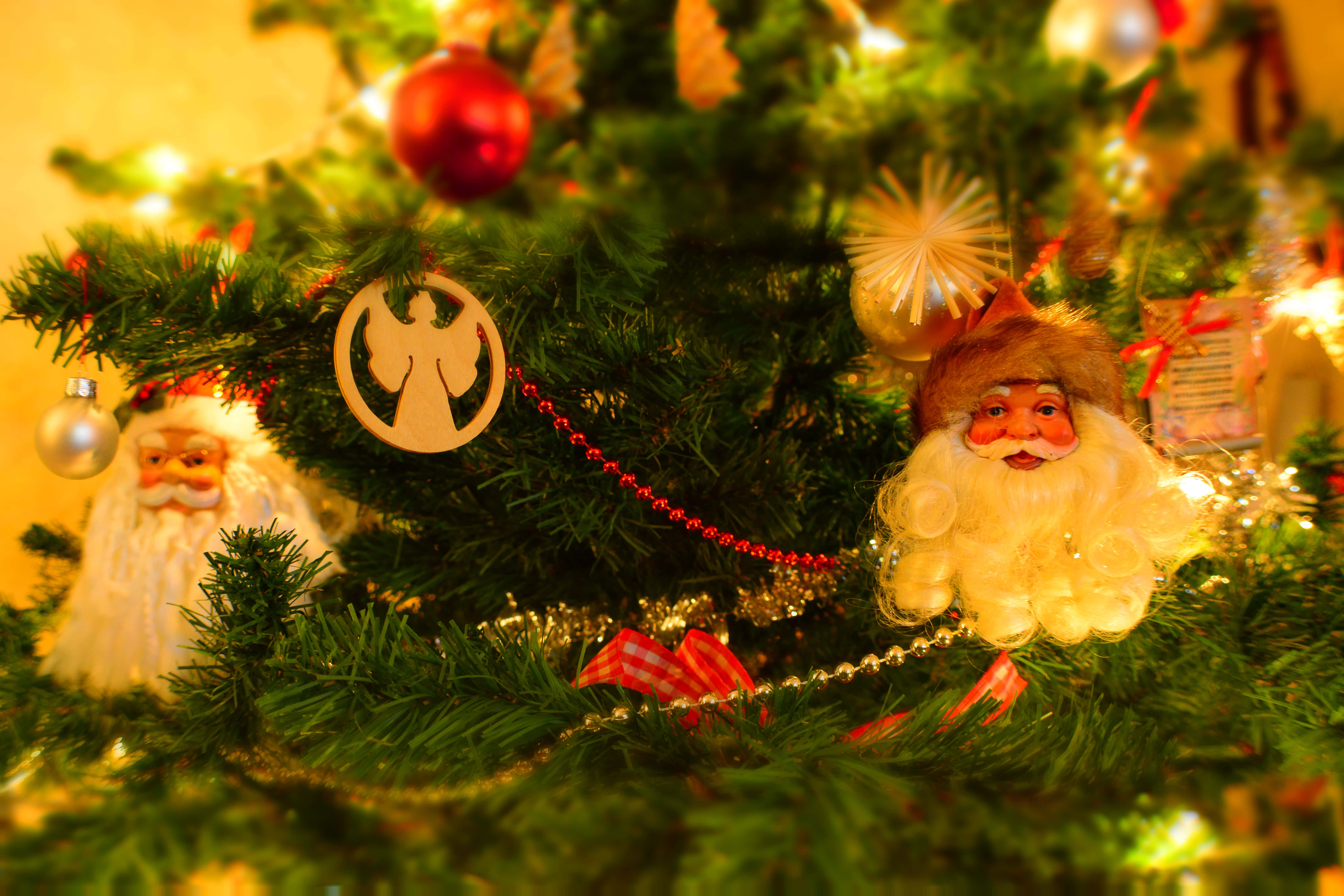 Christmas Tree 桌布 壁紙 — 特寫鏡頭：一棵溫暖照明的聖誕樹，裝飾著聖誕老人公仔、紅色飾物和金色燈光。