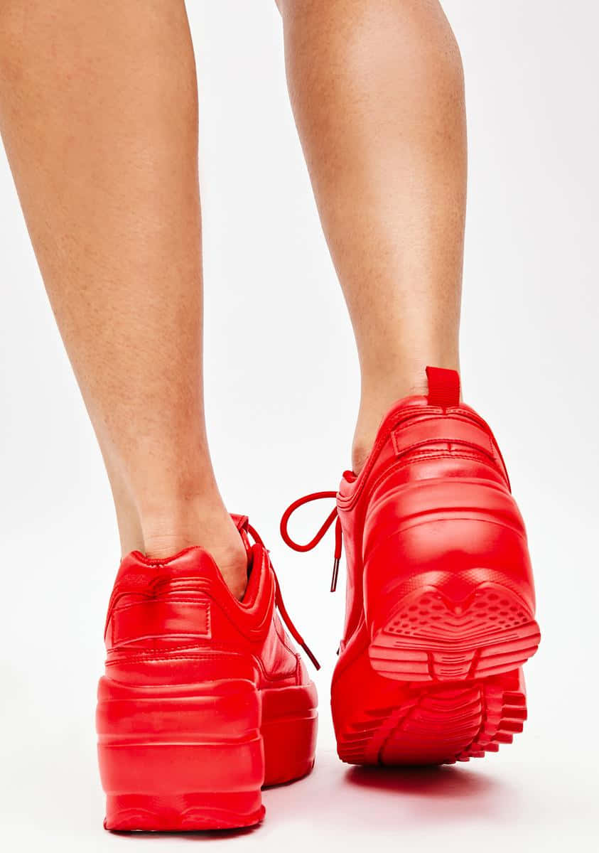 Red Shoes 桌布 壁紙 — 特寫鏡頭：一雙鮮紅色厚底運動鞋穿在人的腳上，背景為純白色。