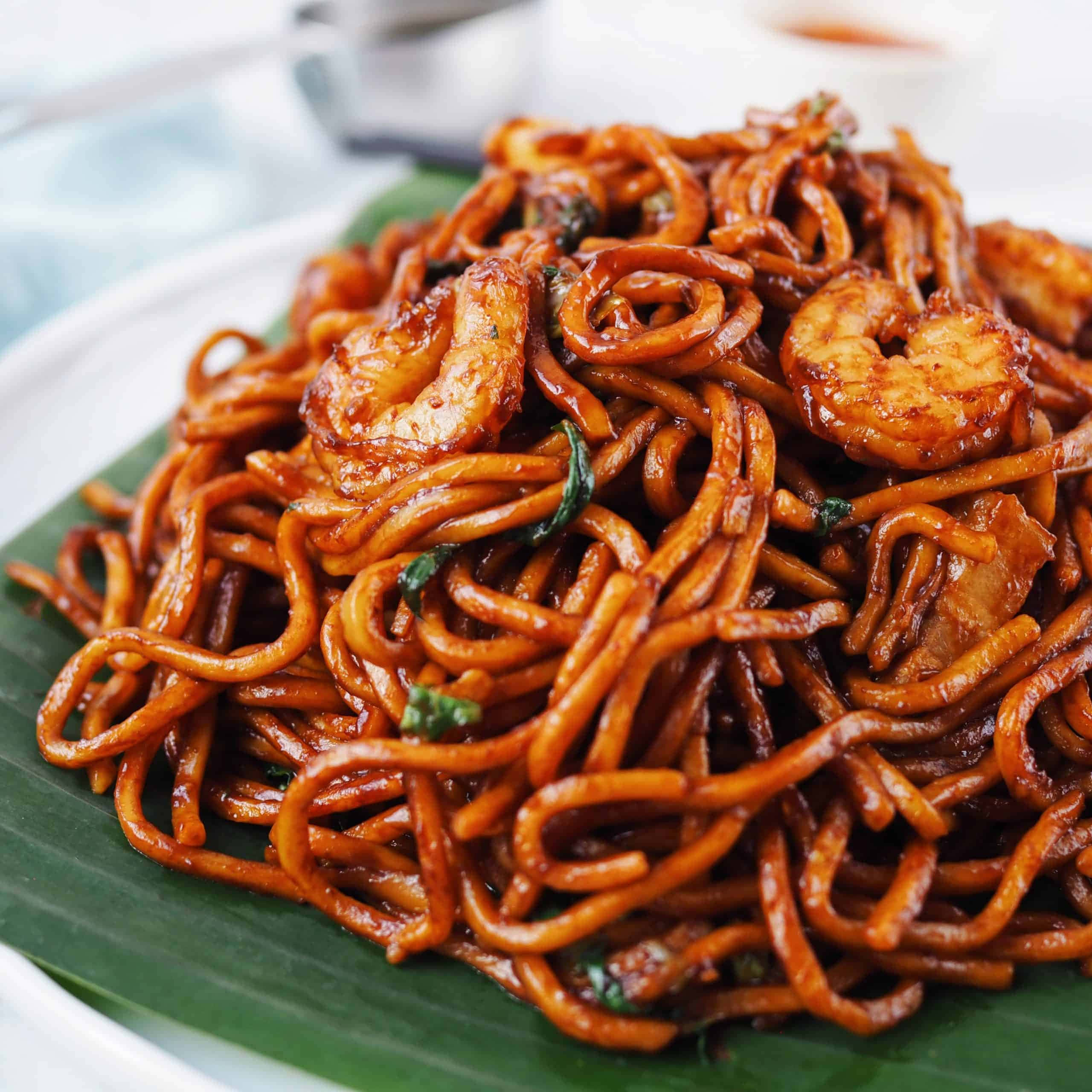 Noodles 桌布 壁紙 — 特寫鏡頭：光澤的炒麵配上蝦仁和香草，盛放在綠色香蕉葉上。
