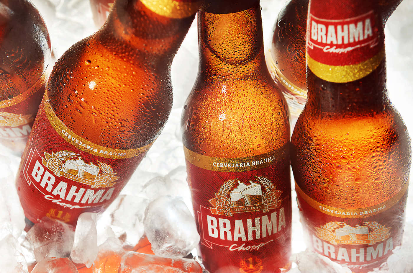 alcohol 桌布 壁紙 — 特寫鏡頭：冰涼的 Brahma 啤酒瓶在冰上出汗，冷凝水珠在明亮燈光下閃閃發光。