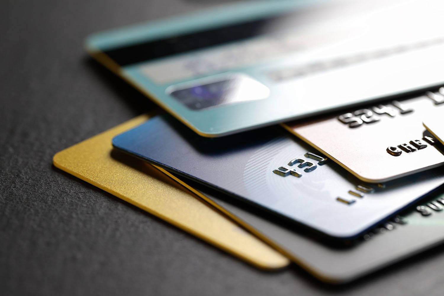 Credit Card 桌布 壁紙 — 特寫鏡頭，各種信用卡在深色紋理表面上呈扇形展開，景深較淺。