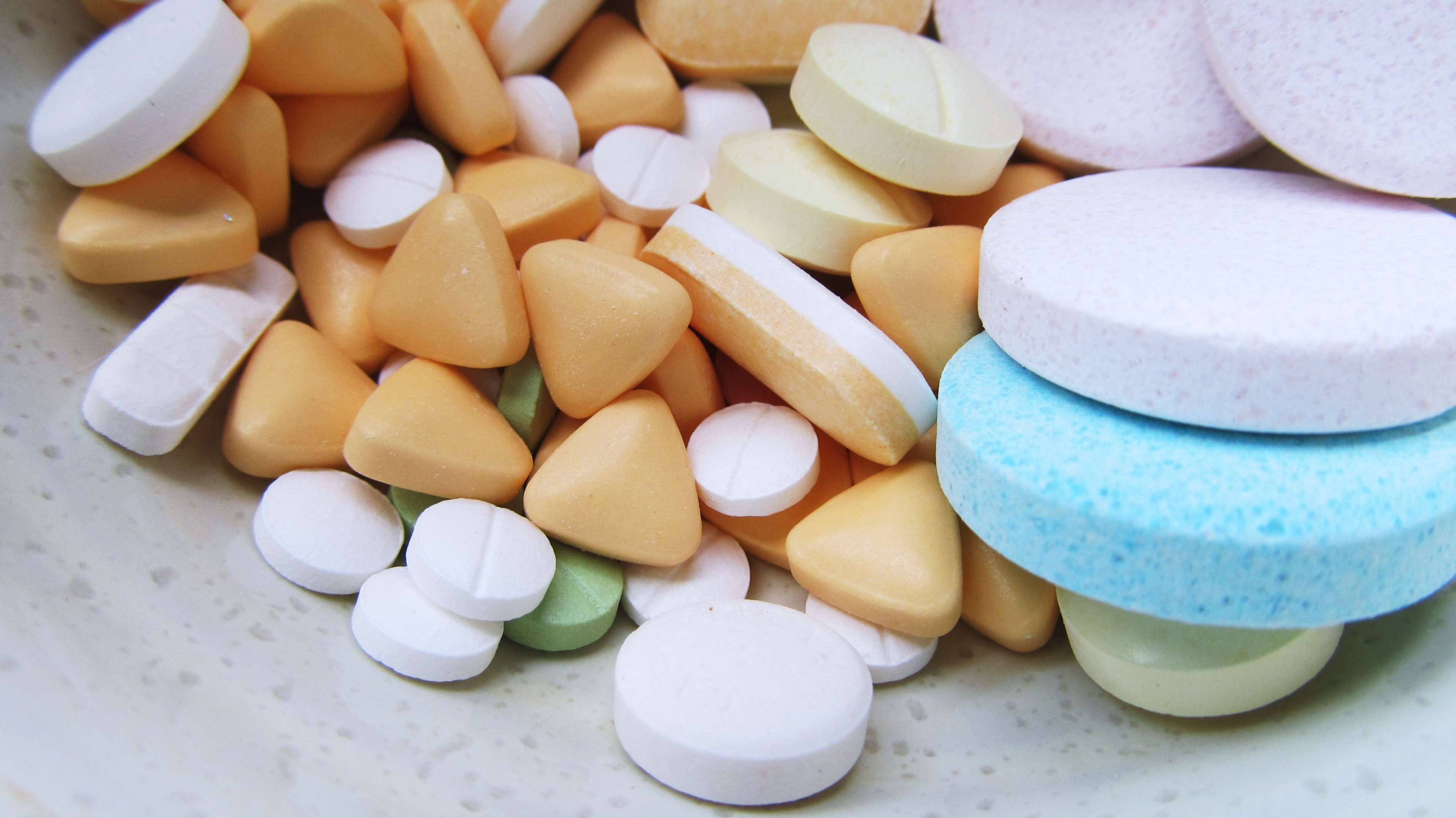 pills 桌布 壁紙 — 特寫鏡頭：各種彩色藥丸和藥片散落在斑點碗中。