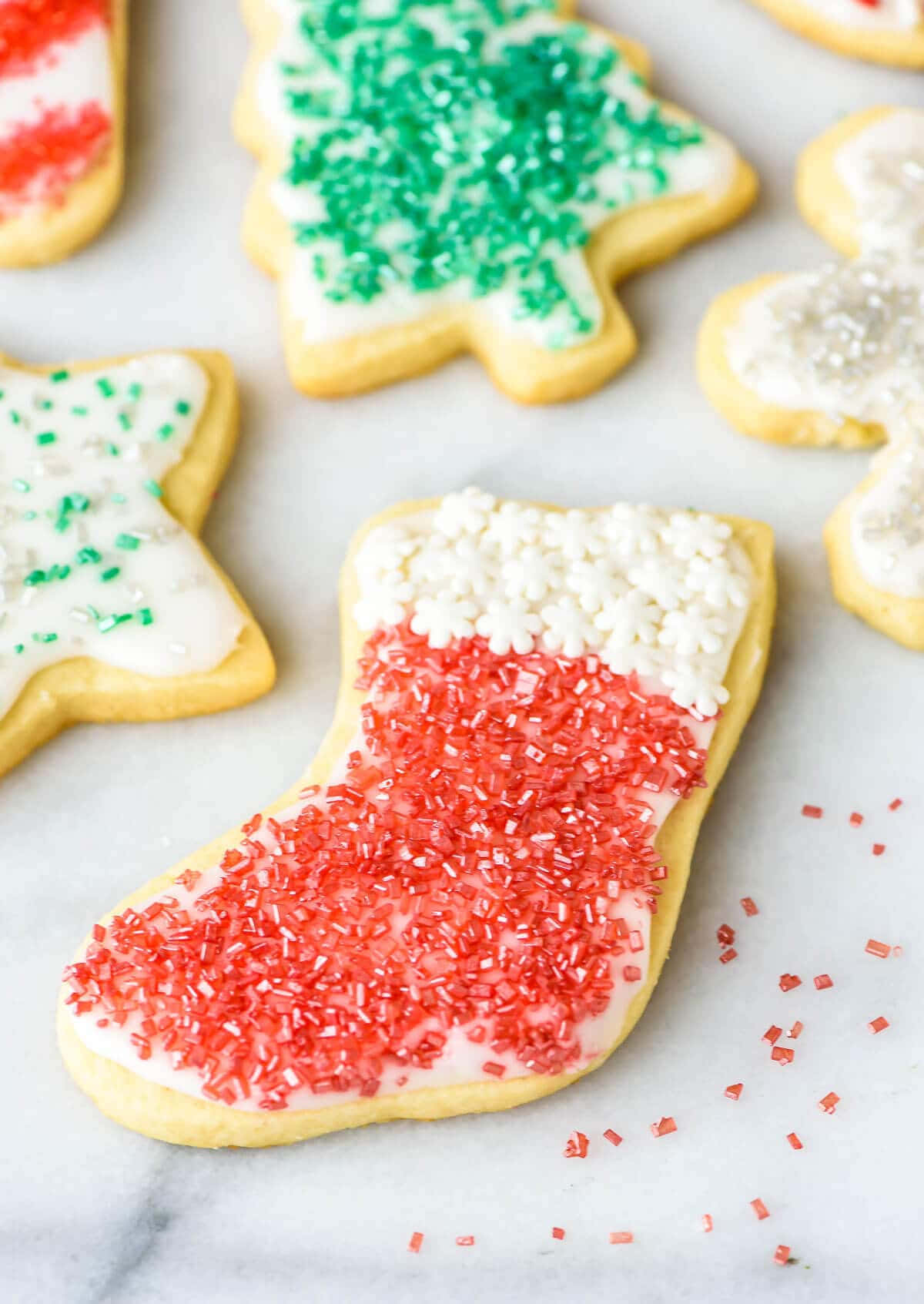 Cookie 桌布 壁紙 — 特寫鏡頭：在大理石表面上，聖誕襪和聖誕樹形狀的節日聖誕餅乾，裝飾著紅色、綠色和白色的糖針。