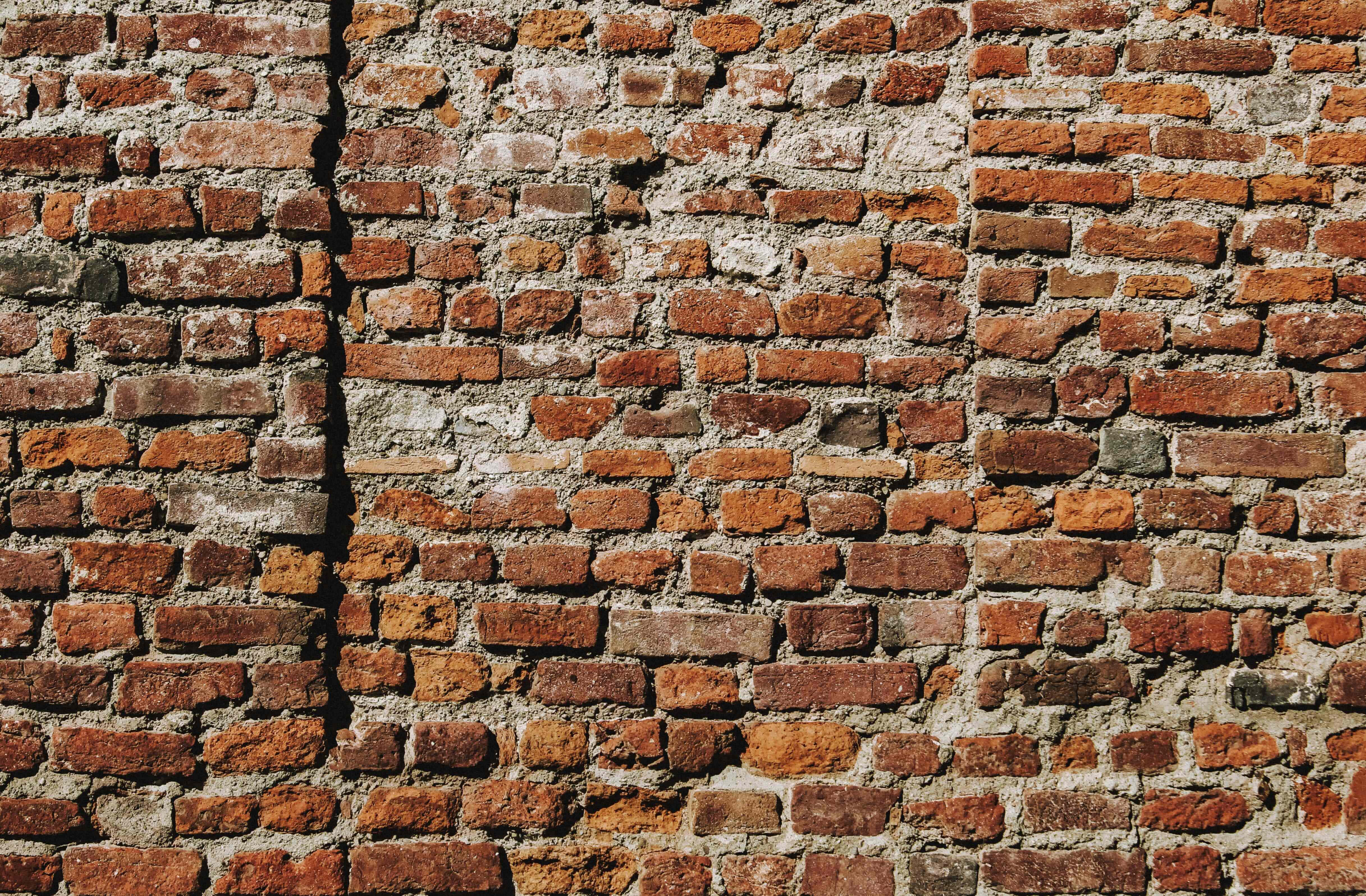 Brick Wall 桌布 壁紙 — 特寫鏡頭：在明亮日光下，風化紅磚牆帶有裂縫砂漿和質樸紋理。