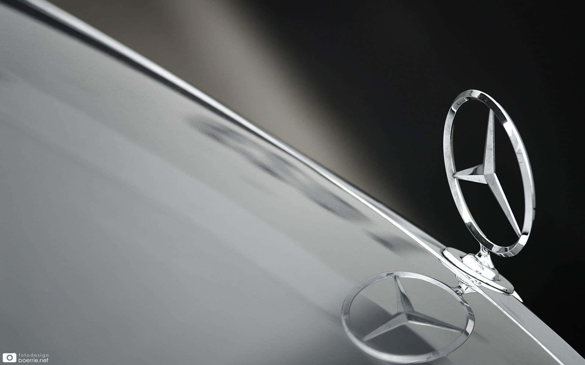Mercedes Benz Logo 桌布 壁紙 — 特寫鏡頭：在深色背景下，銀色汽車引擎蓋上閃閃發光的賓士標誌。