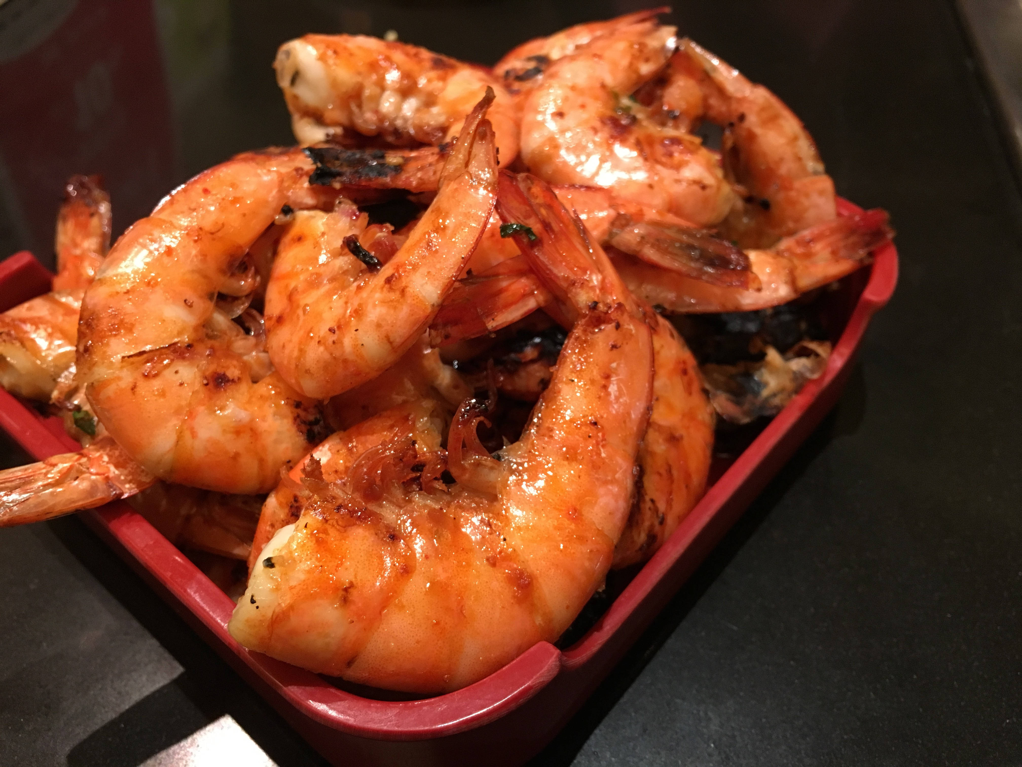 Prawns 桌布 壁紙 — 特寫鏡頭：多汁烤蝦，邊緣焦黑，在紅色盤中閃閃發光。