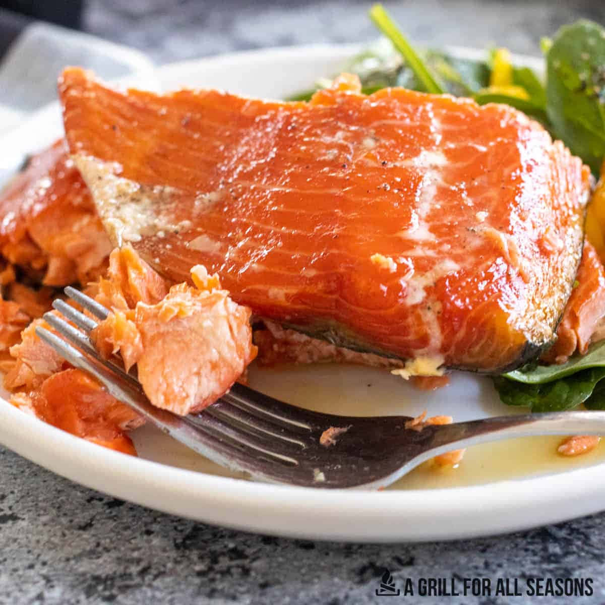 Salmon 桌布 壁紙 — 特寫鏡頭：多汁烤鮭魚排，肉質呈片狀，置於白色盤子上，搭配蔬菜和叉子。