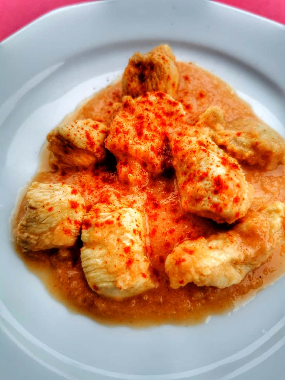 Chicken 桌布 壁紙 — 特寫鏡頭：嫩滑雞塊配上濃郁橙醬，上面灑滿鮮紅香料，盛載於白色碟上。