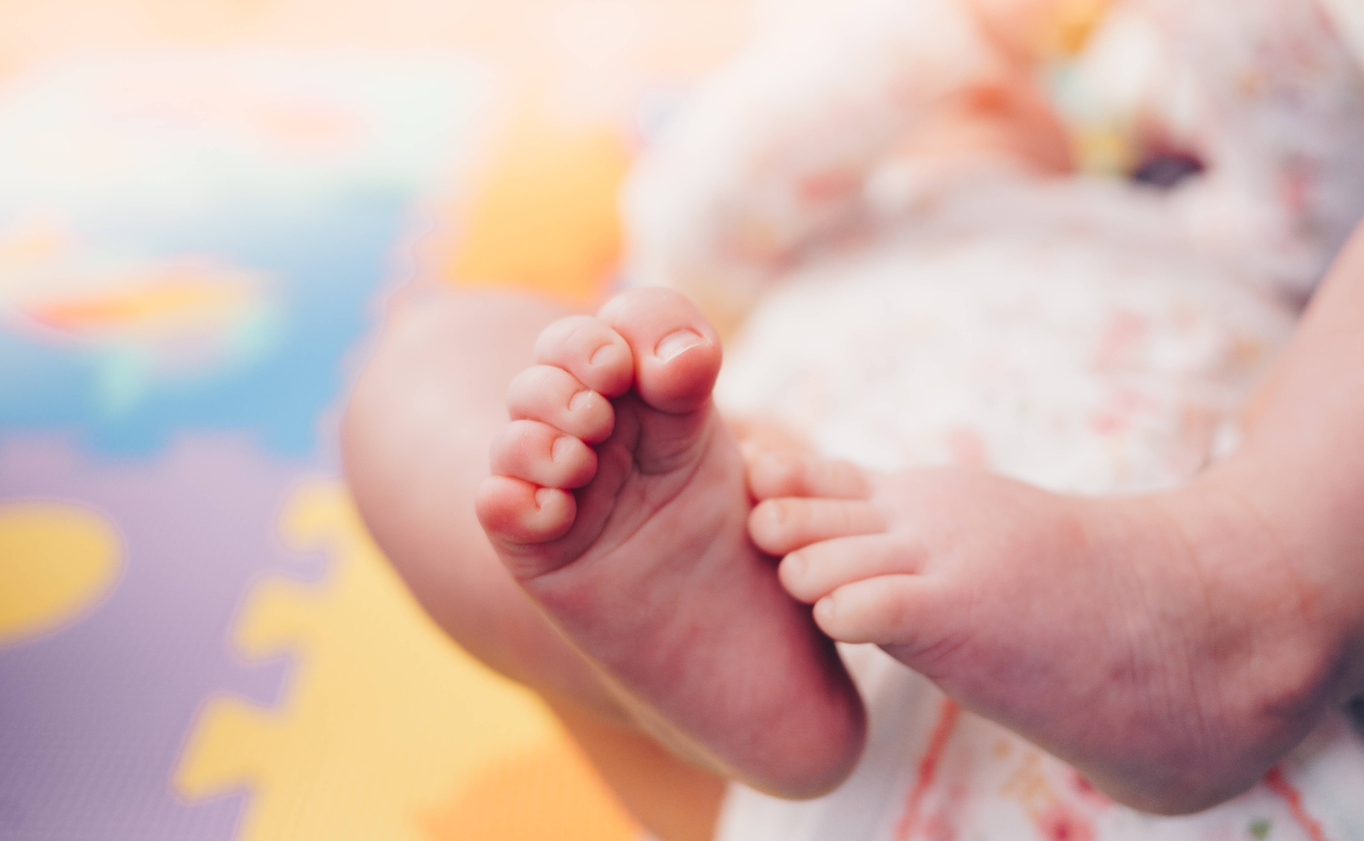 Baby Boy 桌布 壁紙 — 特寫鏡頭：嬰兒的小腳丫放在色彩繽紛的拼圖地墊上，背景柔和模糊。