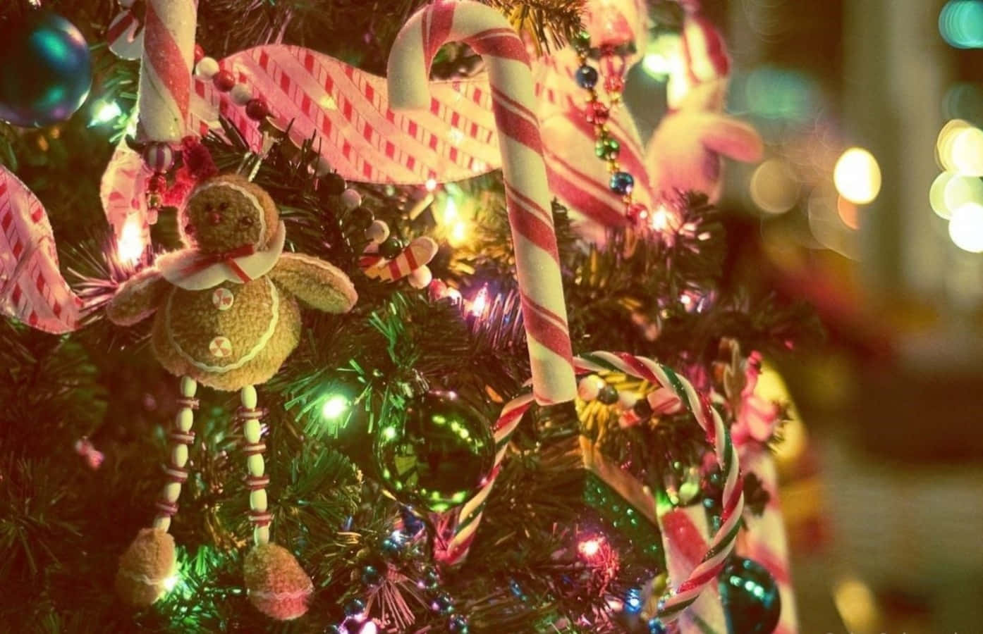 Tumblr Christmas 桌布 壁紙 — 特寫鏡頭，展示一棵節日裝飾的聖誕樹，上面有拐杖糖、薑餅裝飾和閃爍的燈光。