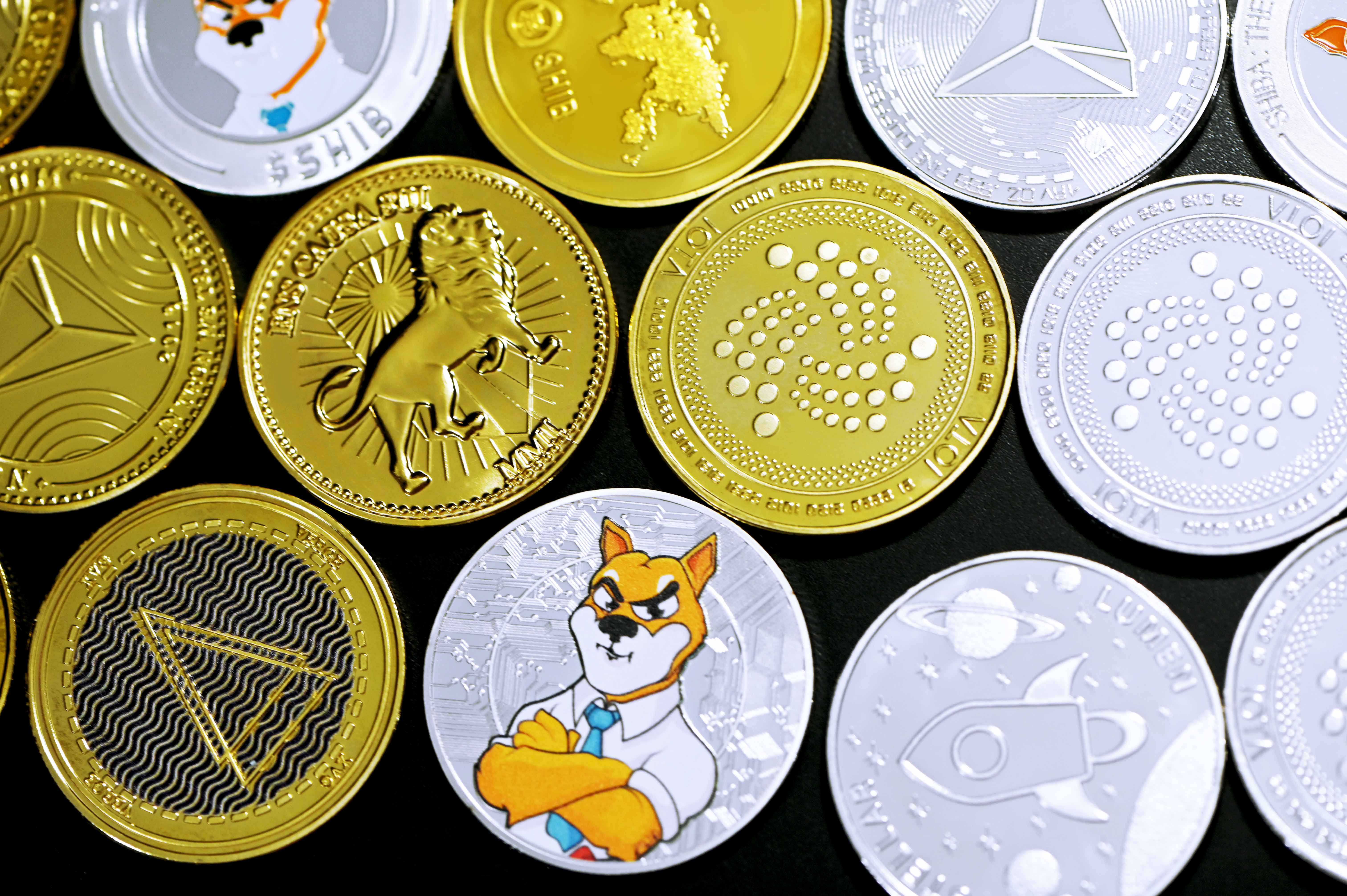 Cryptocurrency 桌布 壁紙 — 特寫鏡頭，展示各種加密貨幣硬幣，包括 Shiba Inu Doge 和其他符號，位於金色和銀色圓盤上，背景為黑色。