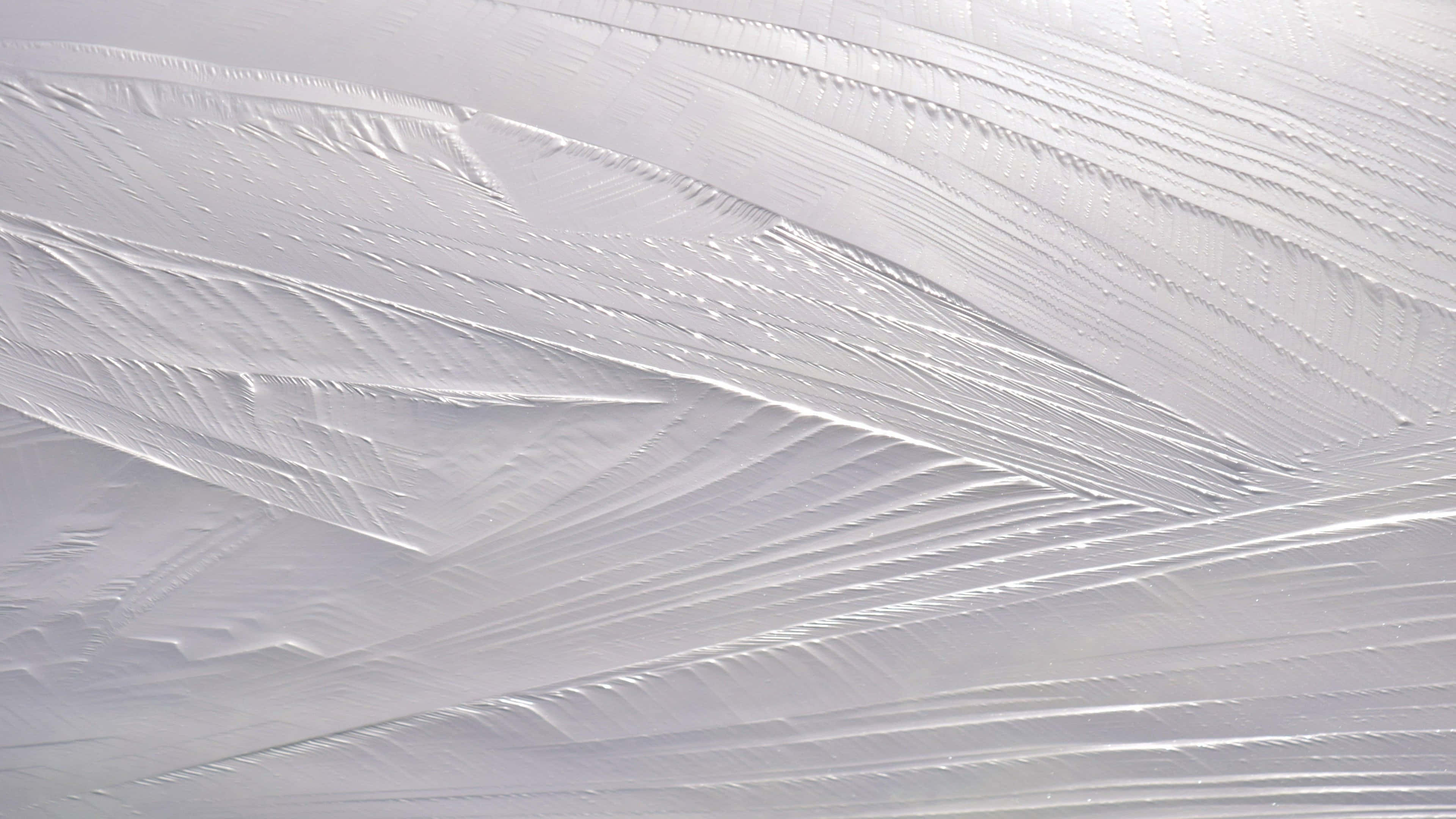 Paint Texture 桌布 壁紙 — 特寫鏡頭，展示在冰冷玻璃表面上形成精緻晶體脊的複雜霜花圖案。