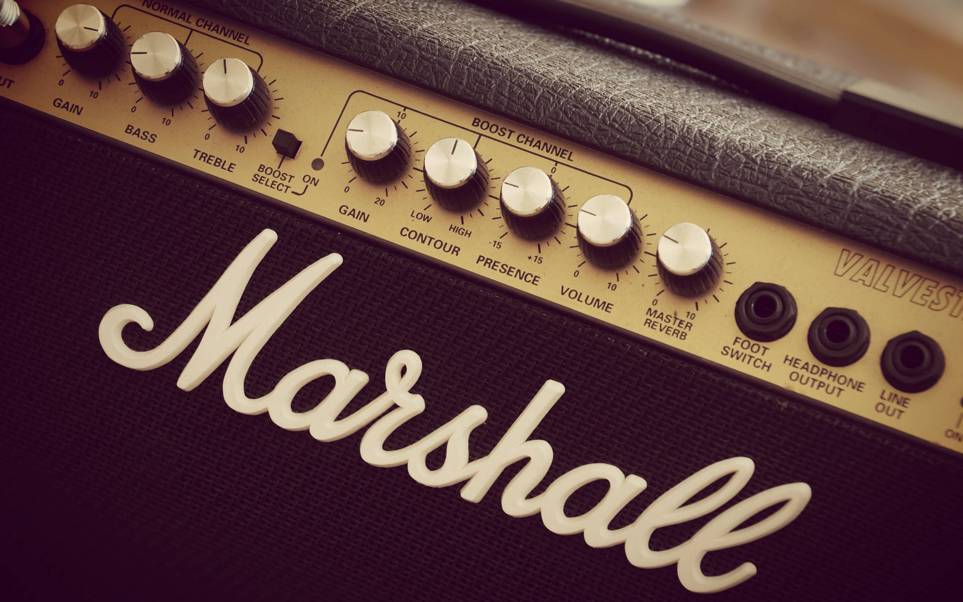 Marshall 桌布 壁紙 — 特寫鏡頭：復古 Marshall 吉他音箱，配以奶油色旋鈕和黑色網布，在溫暖燈光下。