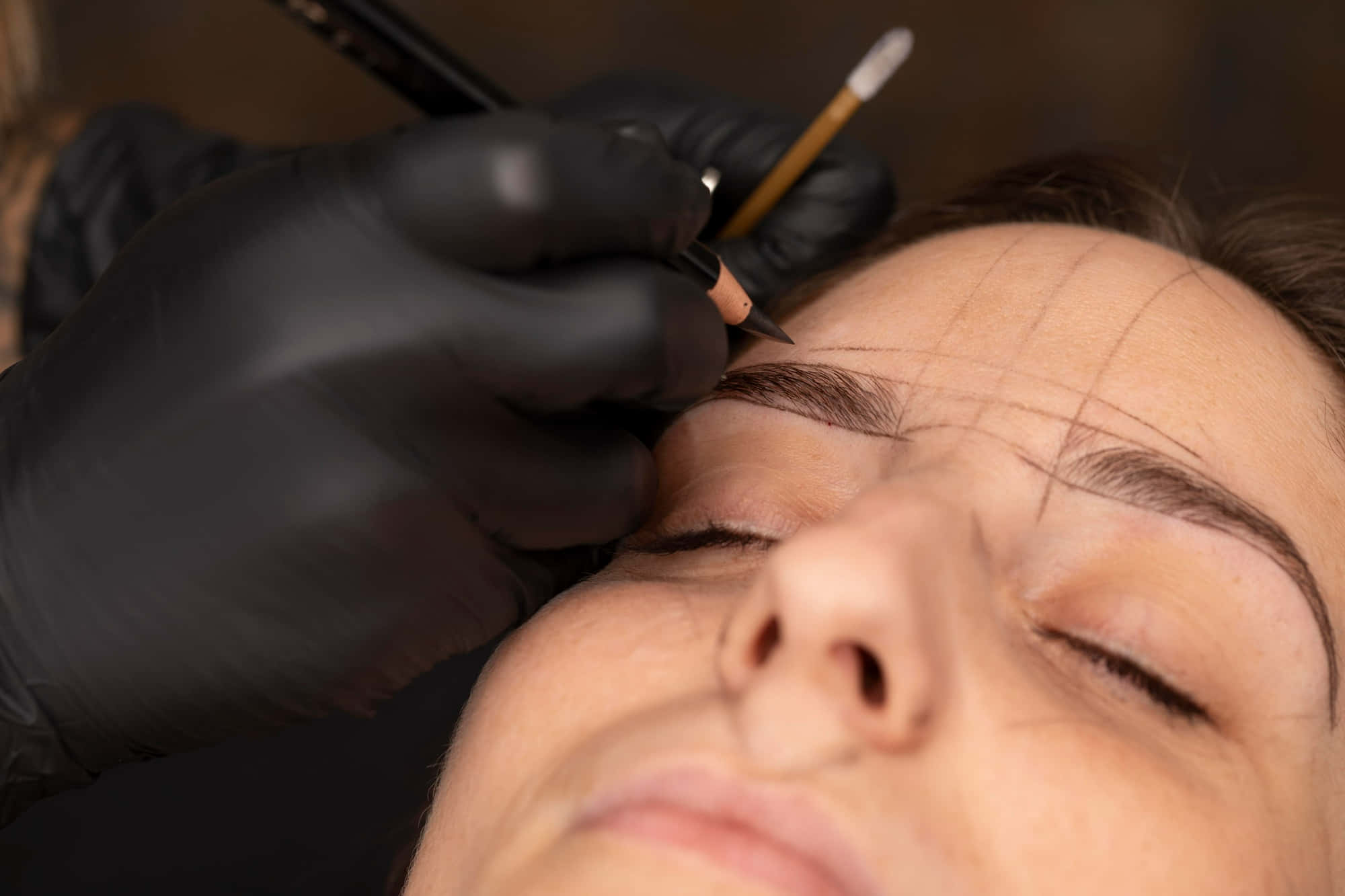 Surgery 桌布 壁紙 — 特寫鏡頭：戴手套的手用細鉛筆在放鬆的客戶臉上描繪精確的眉線。