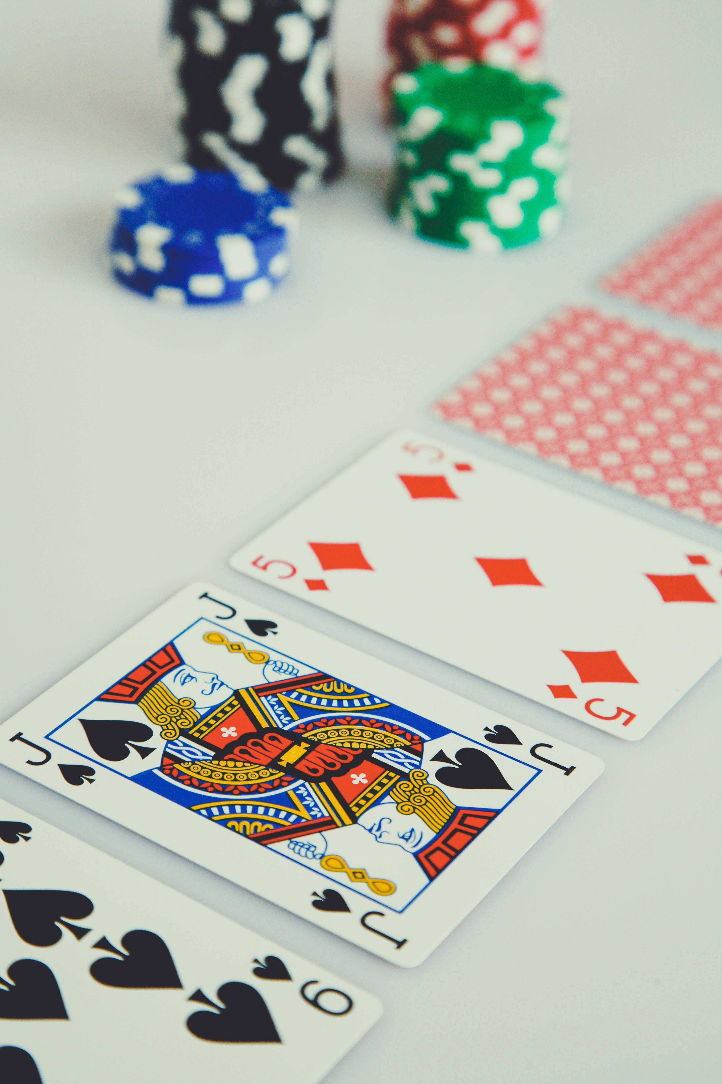 Casino 桌布 壁紙 — 特寫鏡頭：撲克牌與彩色籌碼整齊排列在潔白表面上。