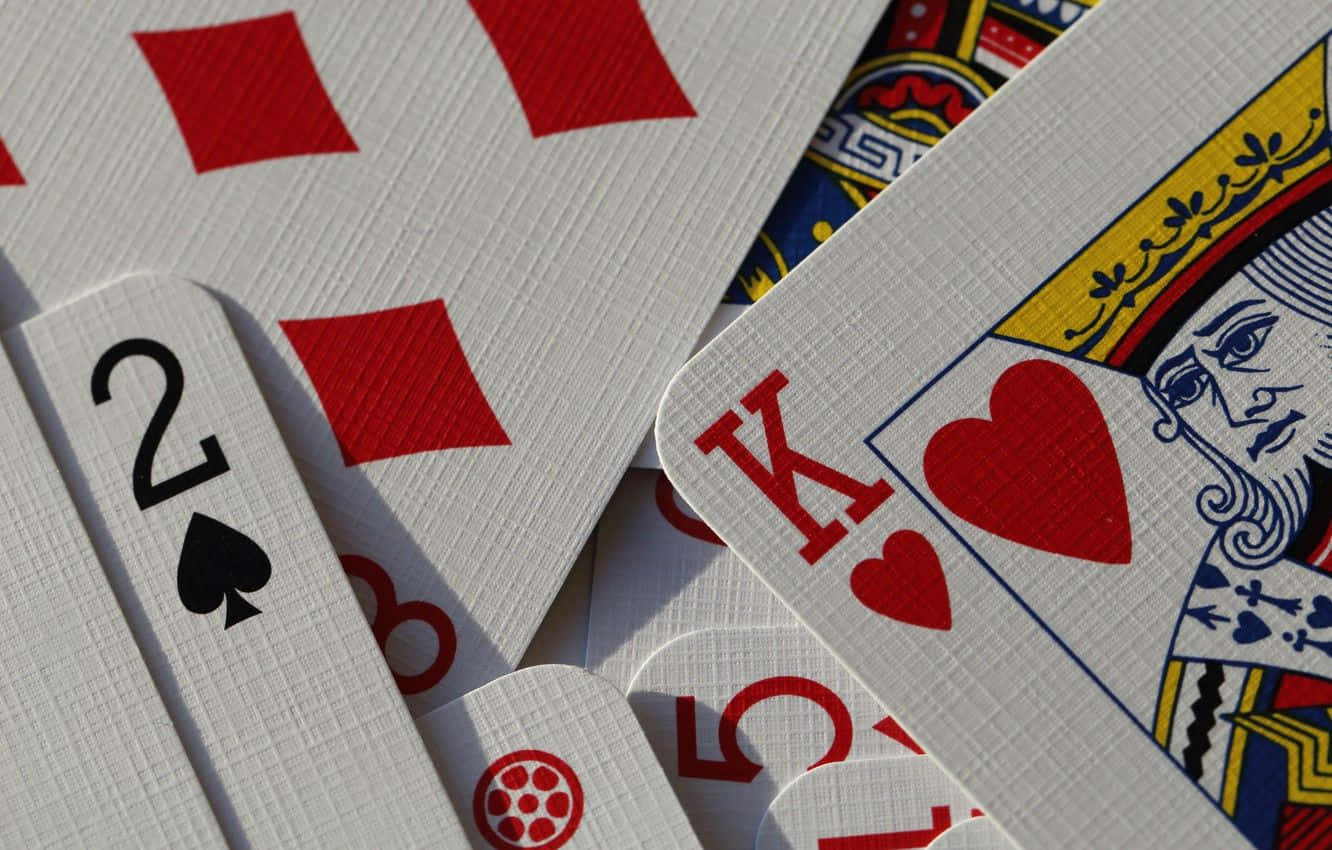 Card Games 桌布 壁紙 — 特寫鏡頭，散落的撲克牌，包括紅心K和黑桃2，在明亮光線下呈現紋理表面。
