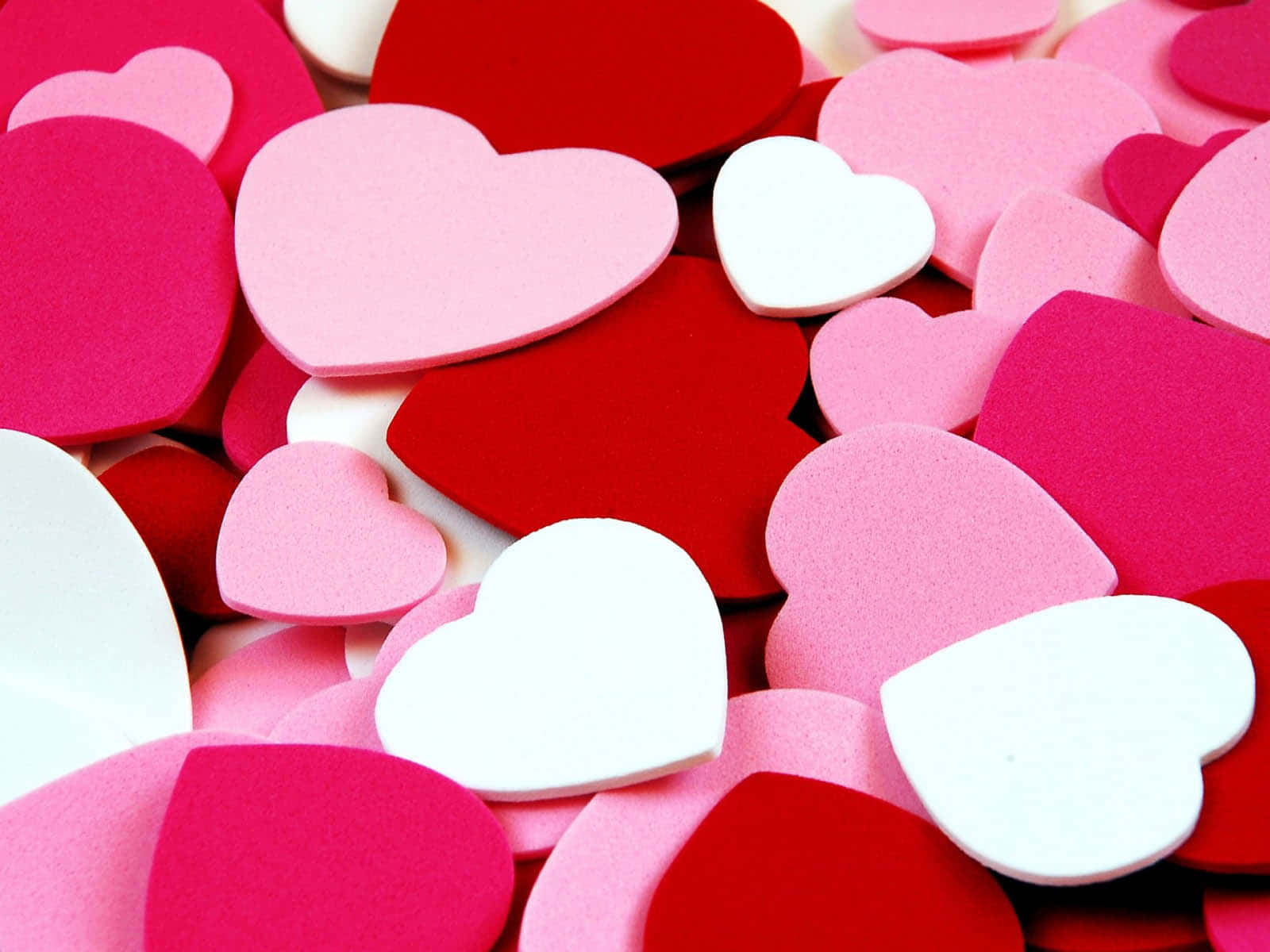 3d Heart 桌布 壁紙 — 特寫鏡頭，散落的紅色、粉紅色和白色泡棉心形，營造出柔軟有質感的情人節背景。