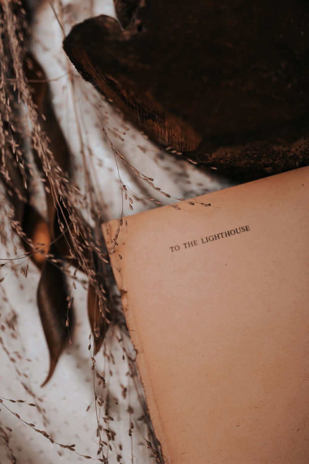 Soft Brown Aesthetic 桌布 壁紙 — 特寫鏡頭，書頁標題為「TO THE LIGHTHOUSE」，藏於乾草和樹葉之間。