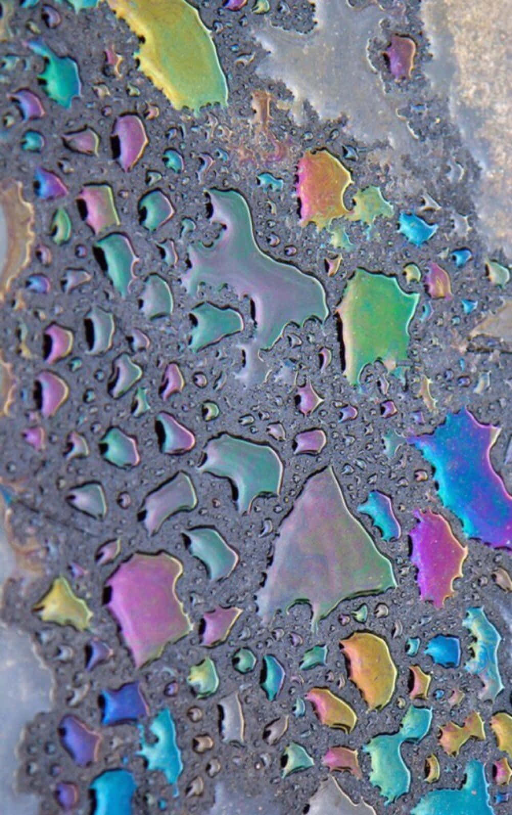 glass 桌布 壁紙 — 特寫鏡頭：水面上虹彩油膜在深色紋理表面上形成鮮豔彩虹圖案。