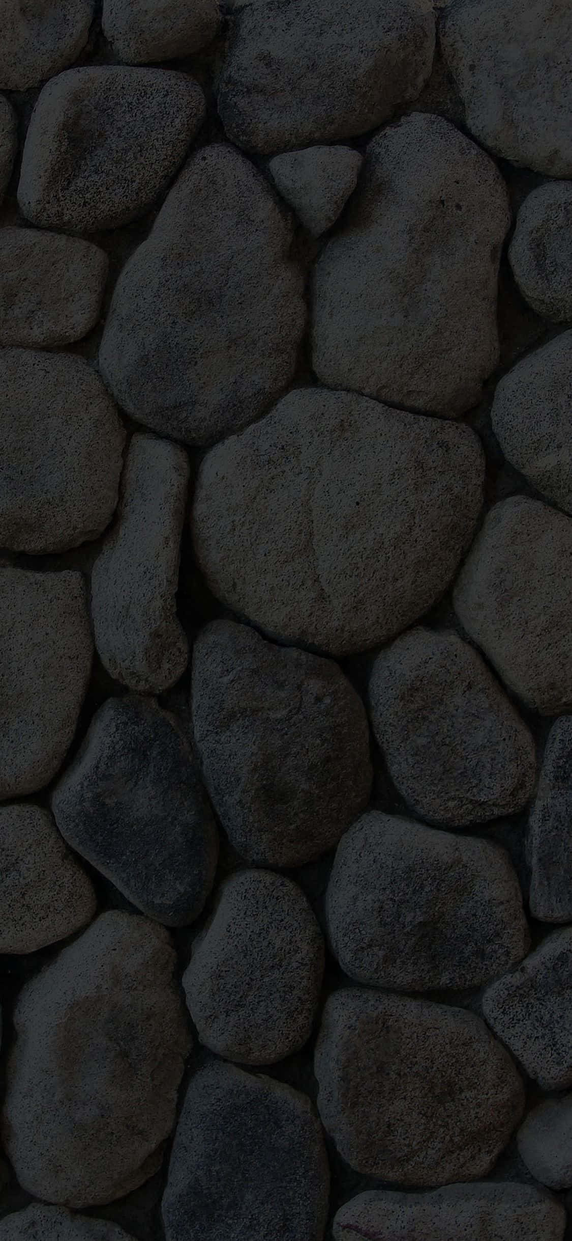 Stone 桌布 壁紙 — 特寫鏡頭：深灰色圓形石頭排列在帶有微妙天然紋理的紋理牆上。