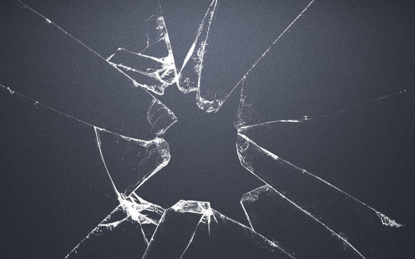 Screen 桌布 壁紙 — 特寫鏡頭：深灰色背景上，一塊碎裂的玻璃，從中央撞擊點放射出尖銳的白色裂紋。