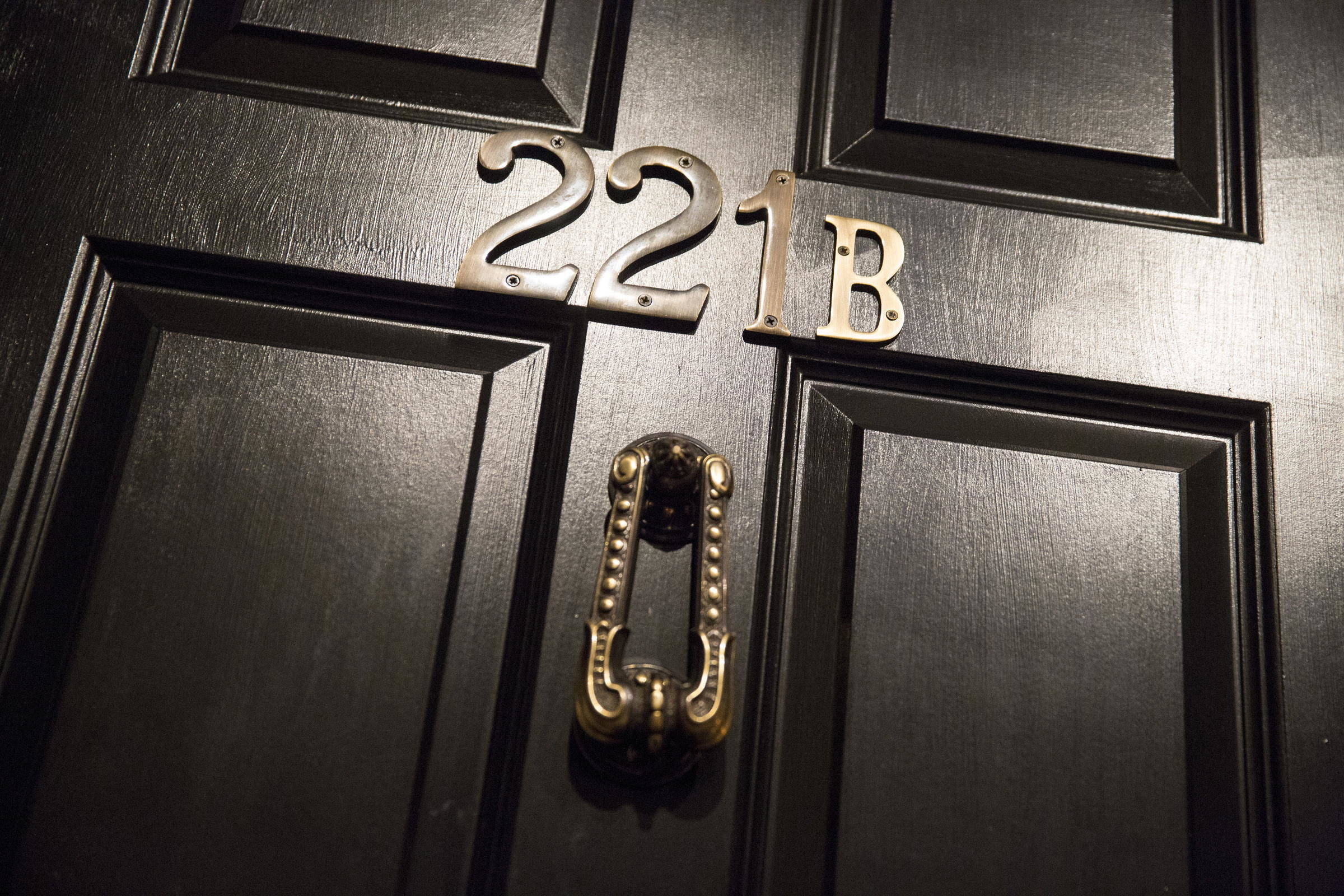 Sherlock Holmes 桌布 壁紙 — 特寫鏡頭：深色木門，黃銅門環和門牌號碼221B在溫暖燈光下閃閃發光。