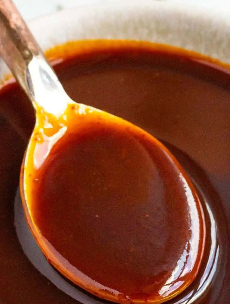 Szechuan Sauce 桌布 壁紙 — 特寫鏡頭，湯匙從陶瓷碗中舀起光澤濃郁的棕色醬汁。