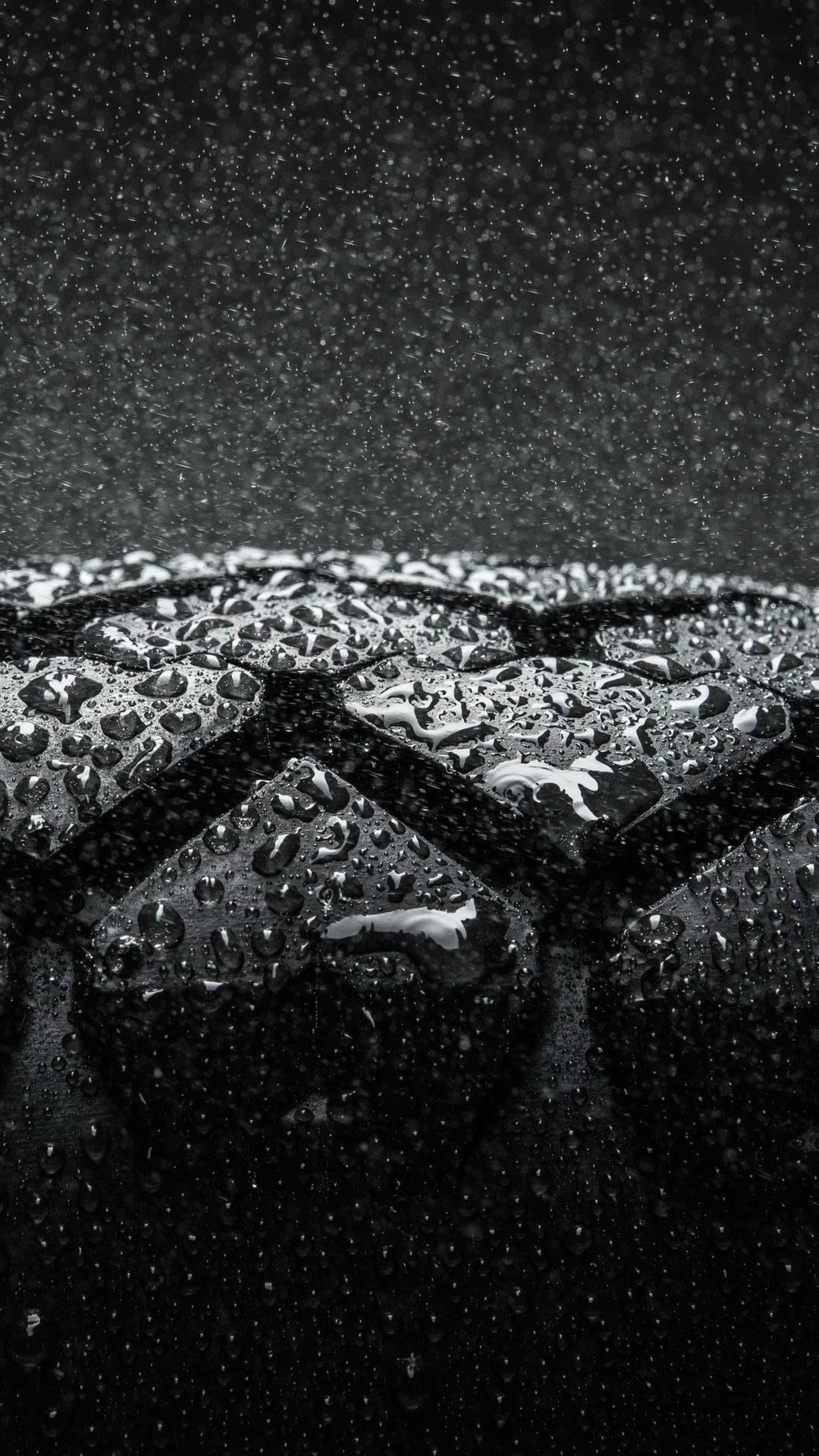 桌布 壁紙 — 特寫鏡頭：潮濕輪胎胎面，雨滴在昏暗光線下閃閃發光，背景漆黑。