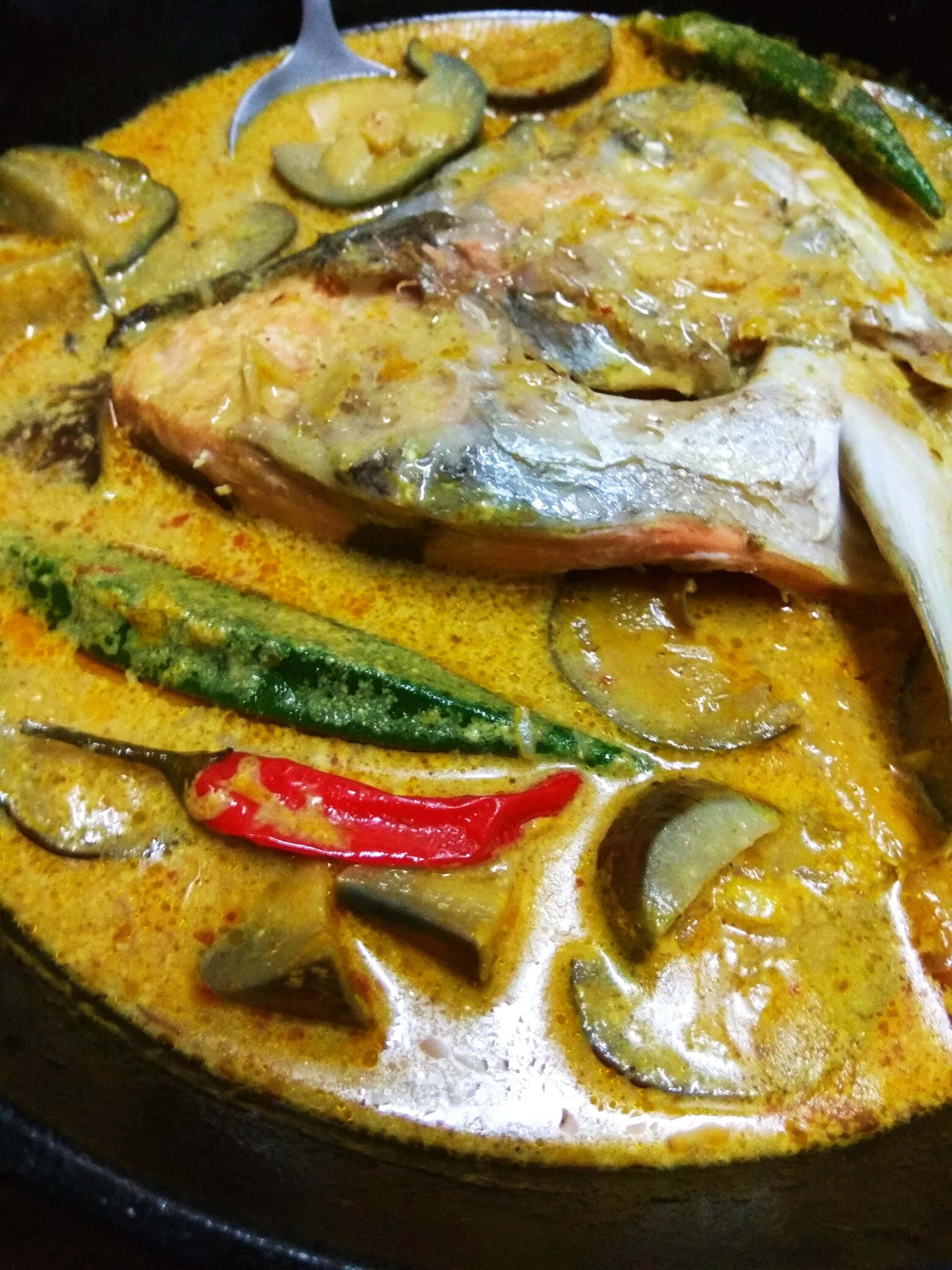 Food Photography 桌布 壁紙 — 特寫鏡頭：濃郁黃咖哩，魚頭、秋葵和紅辣椒在深色鍋中慢煮。