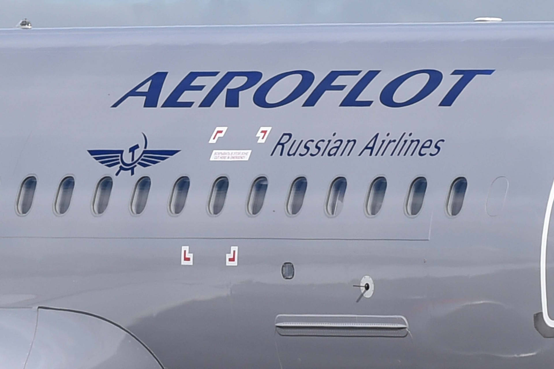  壁紙 — 特寫鏡頭：灰色俄羅斯航空（Aeroflot Russian Airlines）機身，在明亮日光下展示窗戶和標誌。