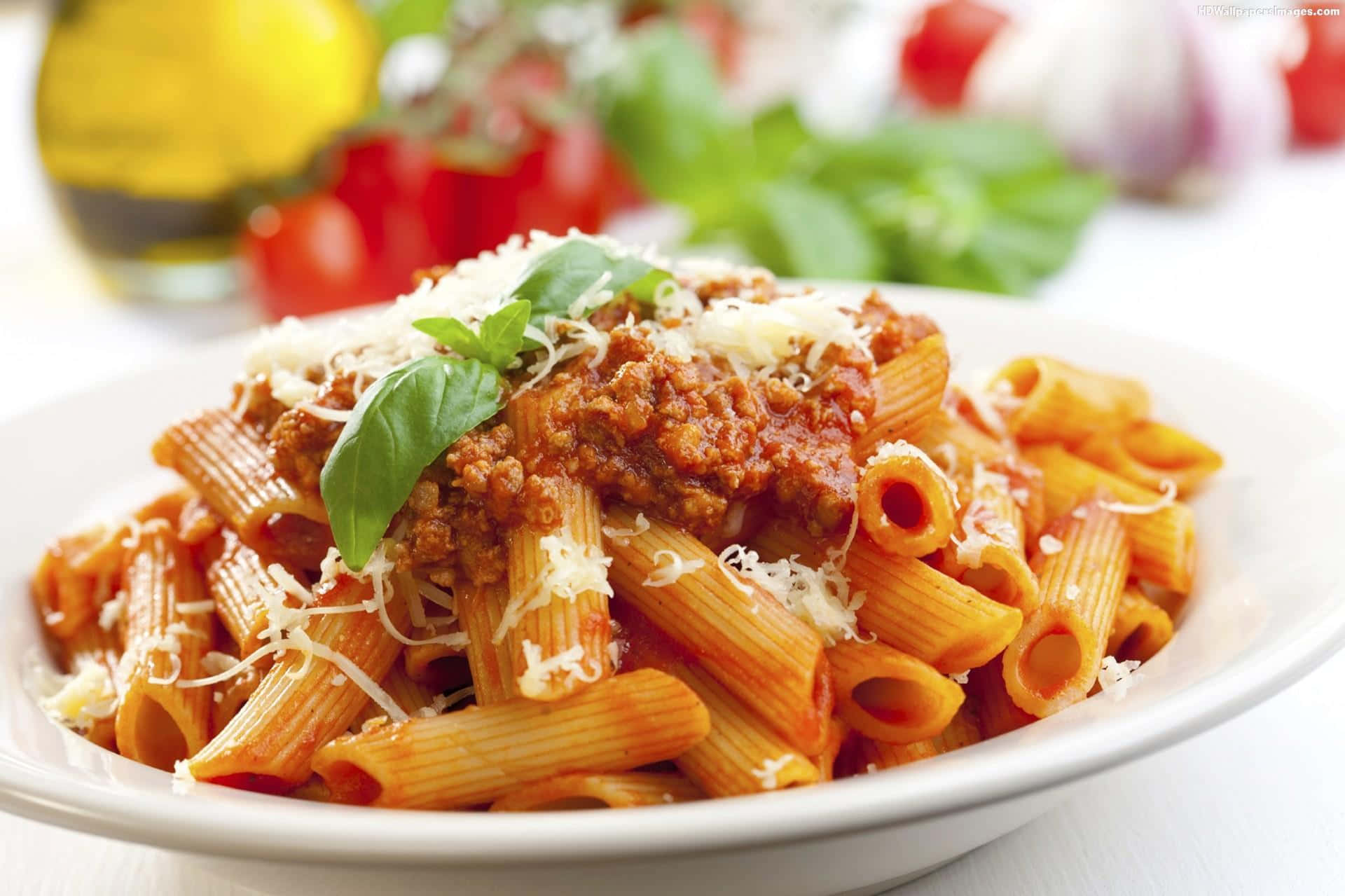 Pasta 桌布 壁紙 — 特寫鏡頭：筆管麵搭配濃郁肉醬，撒上磨碎起司和新鮮羅勒葉。