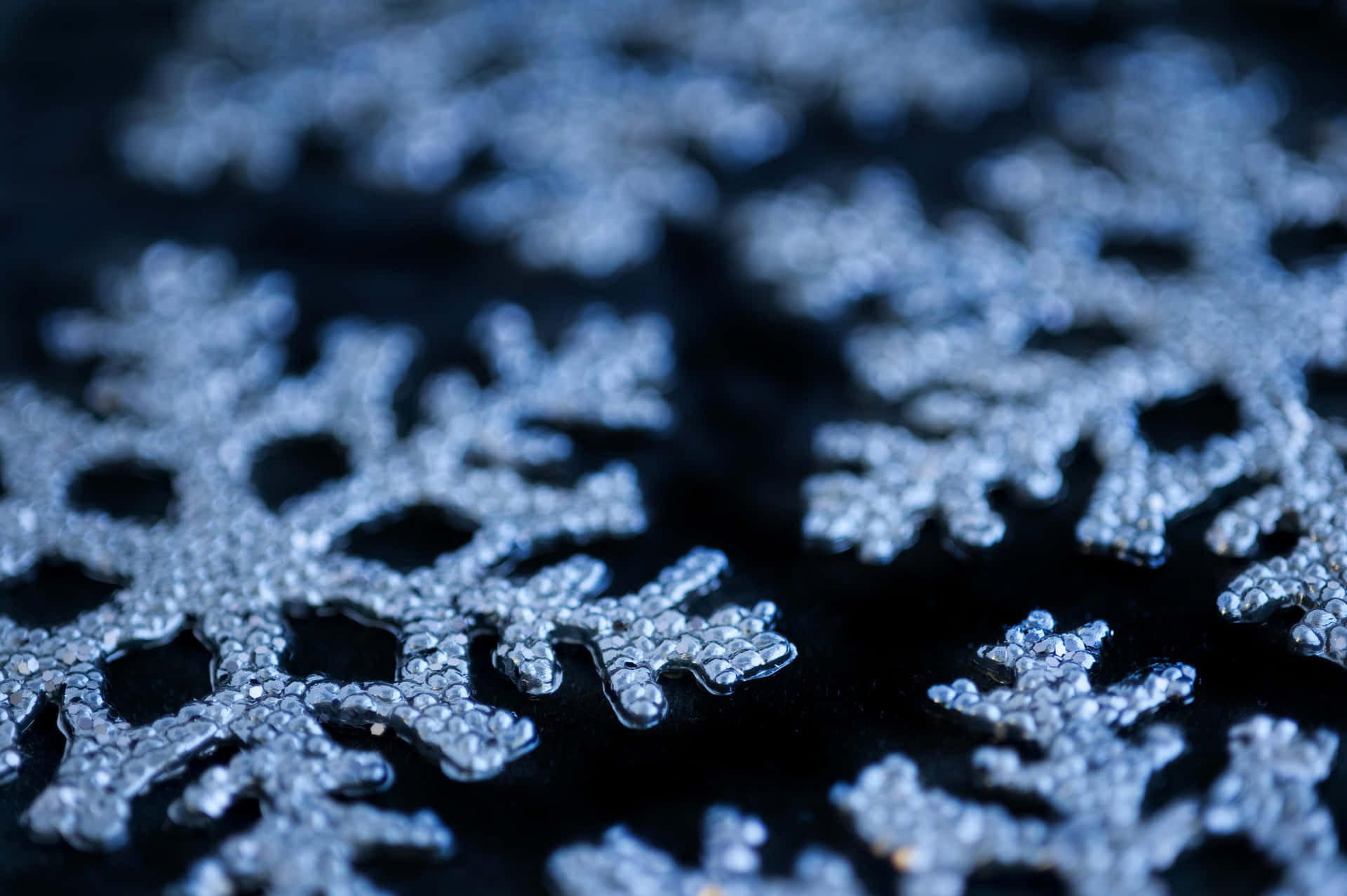 雪花 桌布 壁紙 — 特寫鏡頭，精緻的銀色雪花裝飾品在深黑色背景上柔和發光。