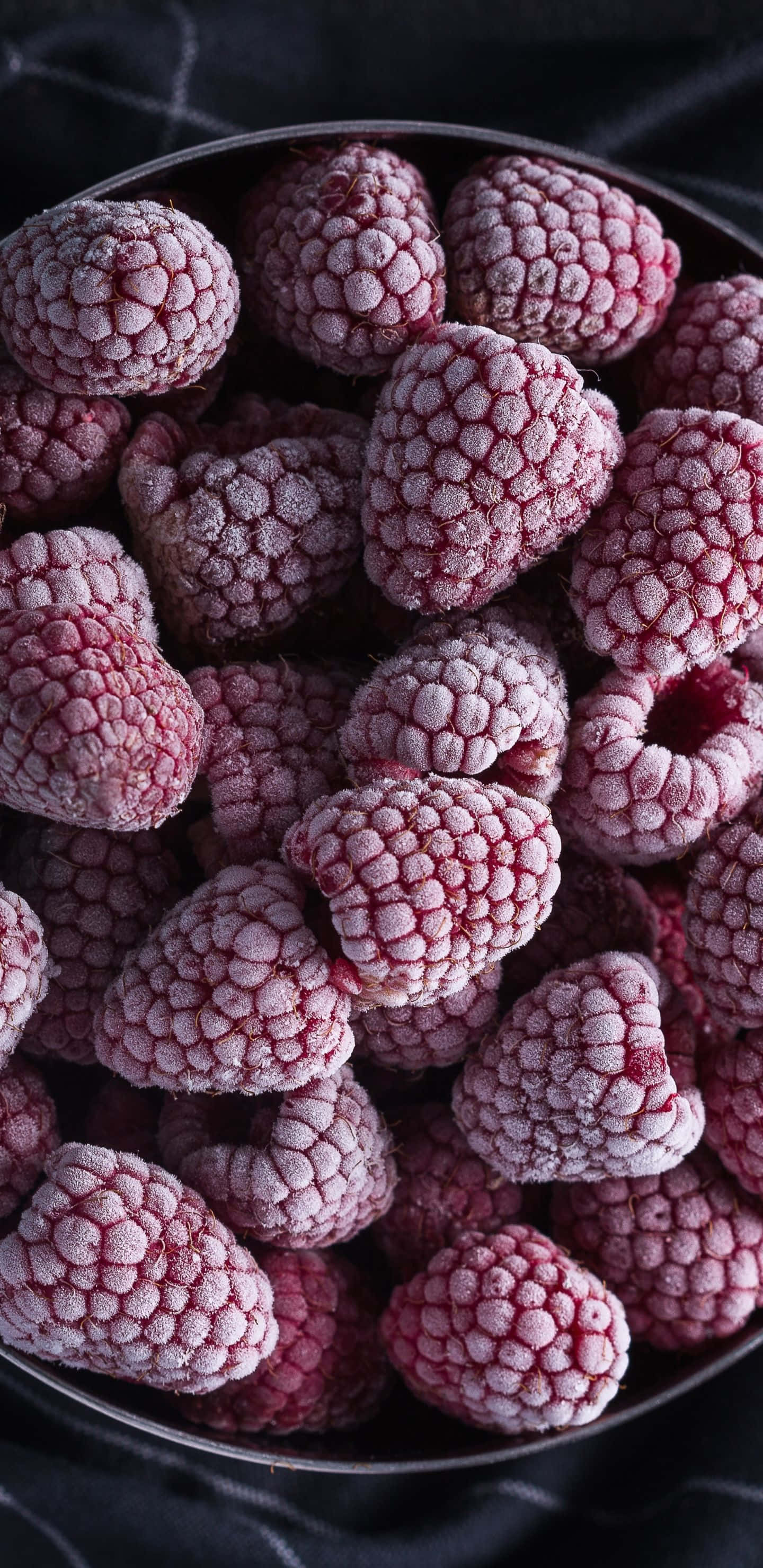 Raspberry 桌布 壁紙 — 特寫鏡頭：結霜的覆盆子堆放在金屬碗中，背景為深色紋理。