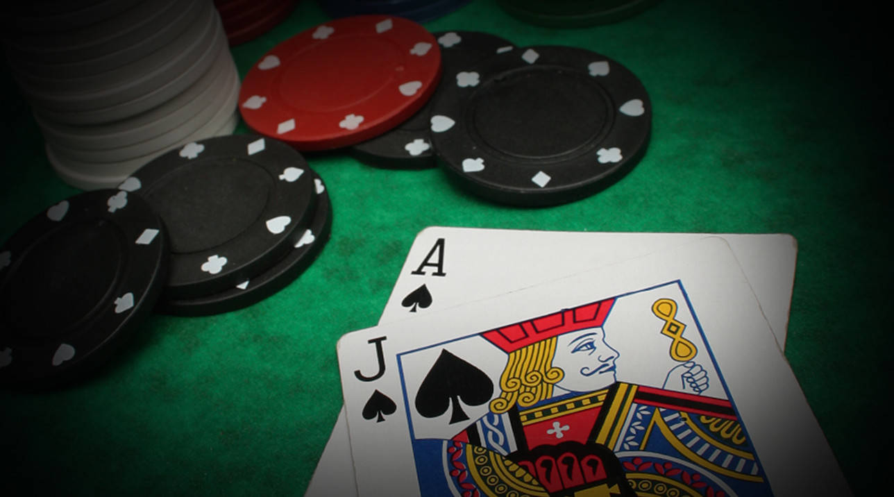 Casino 桌布 壁紙 — 特寫鏡頭：綠色氈桌面上，籌碼與黑桃A及J在戲劇性燈光下。