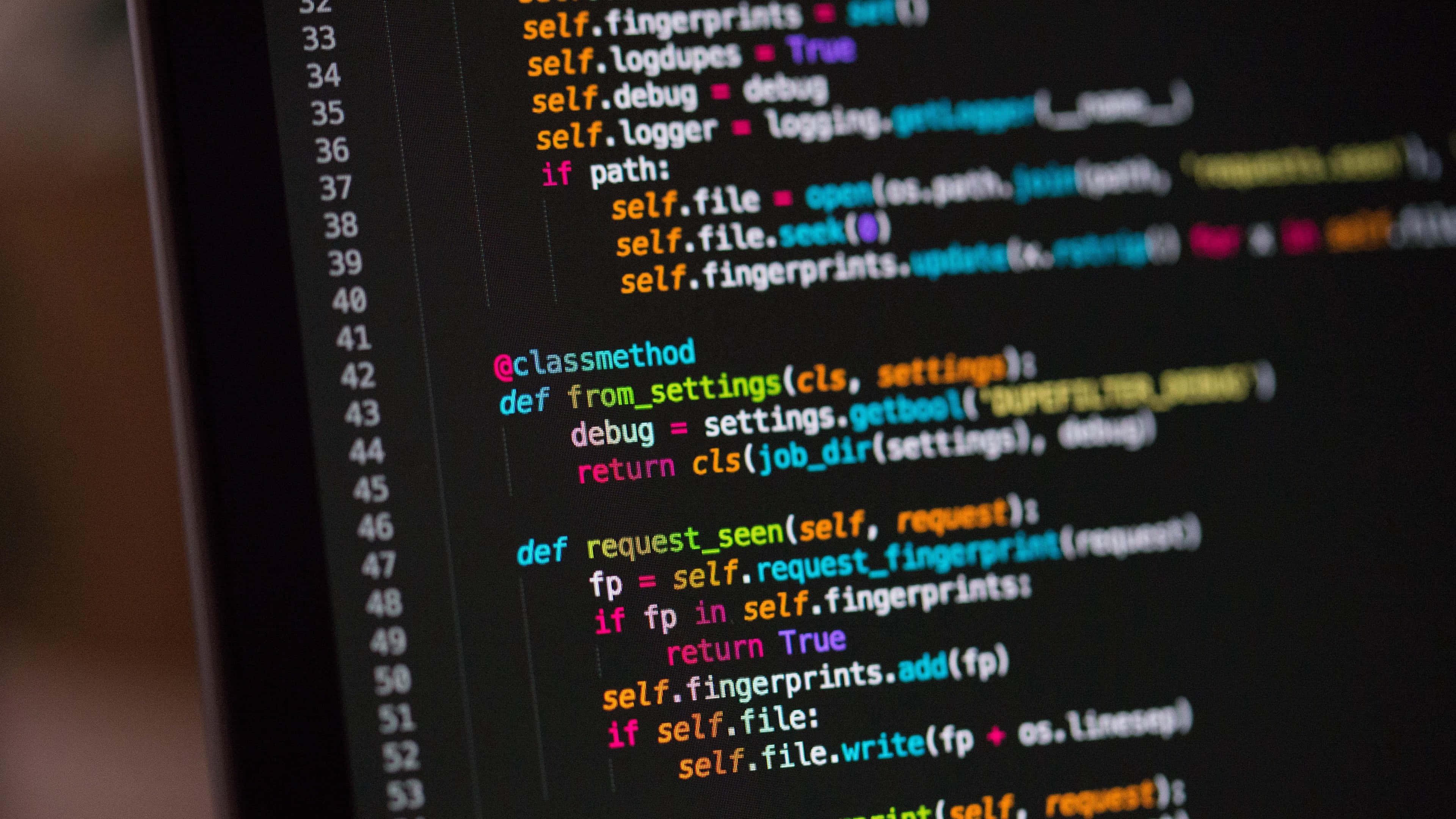 極高畫質 桌布 壁紙 — 特寫鏡頭：色彩繽紛的 Python 程式碼在深色顯示器螢幕上滾動，背景模糊。