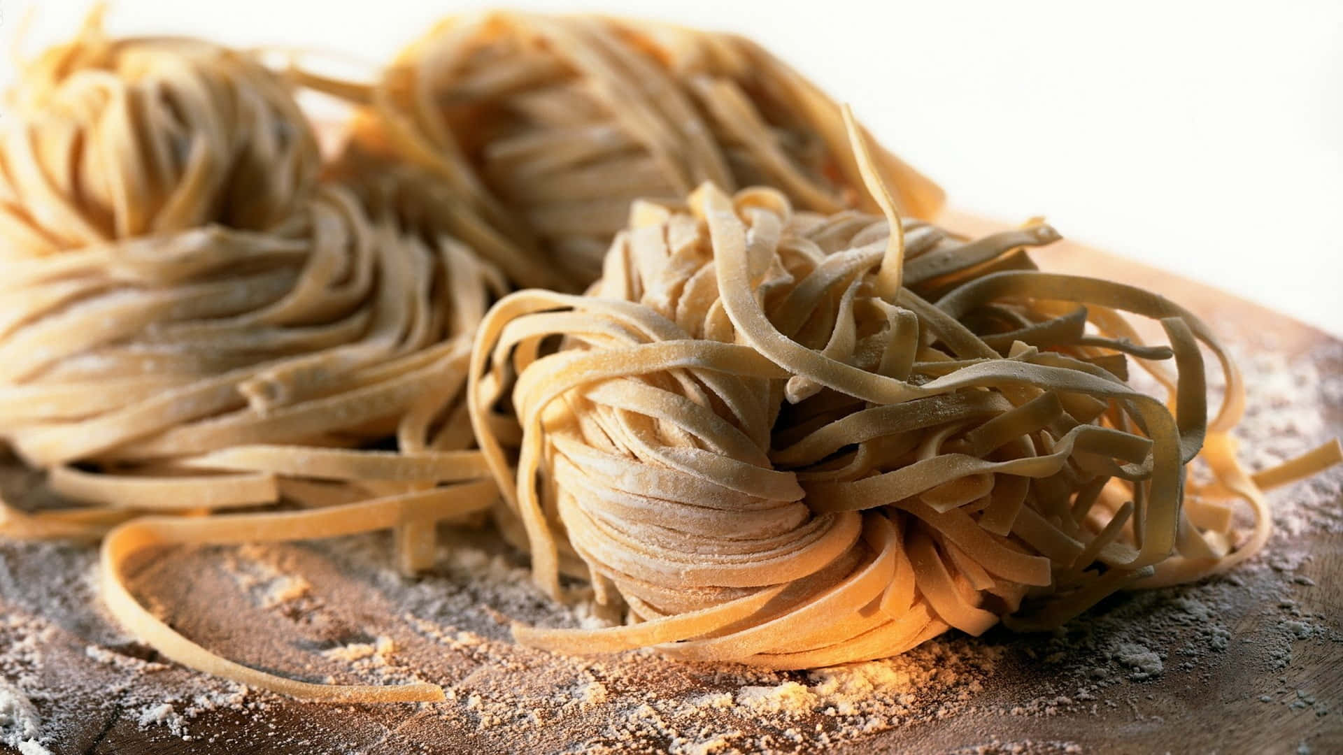 Italian 桌布 壁紙 — 特寫鏡頭：金黃色小麥義大利麵巢撒上麵粉，放在質樸木板上。