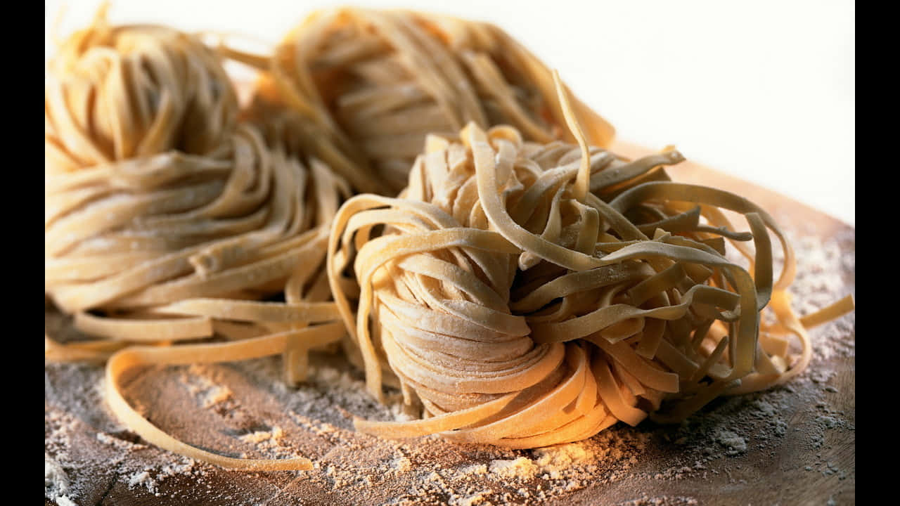 720p Pasta 桌布 壁紙 — 特寫鏡頭：金黃色新鮮義大利麵糰撒上麵粉，置於鄉村風木質表面上。