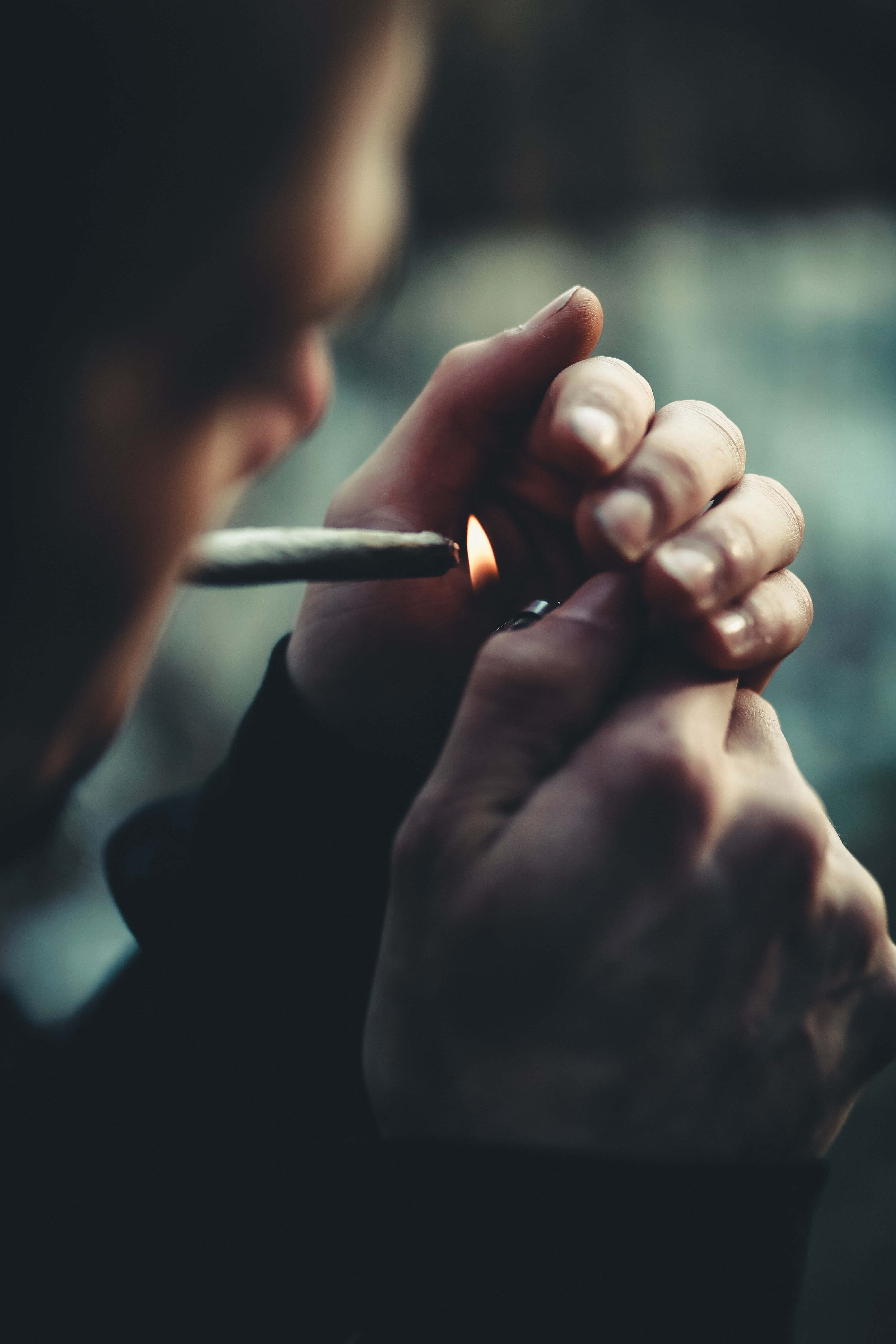 Addiction 桌布 壁紙 — 特寫鏡頭，雙手在模糊的黑暗背景下用閃爍的火焰點燃大麻煙。