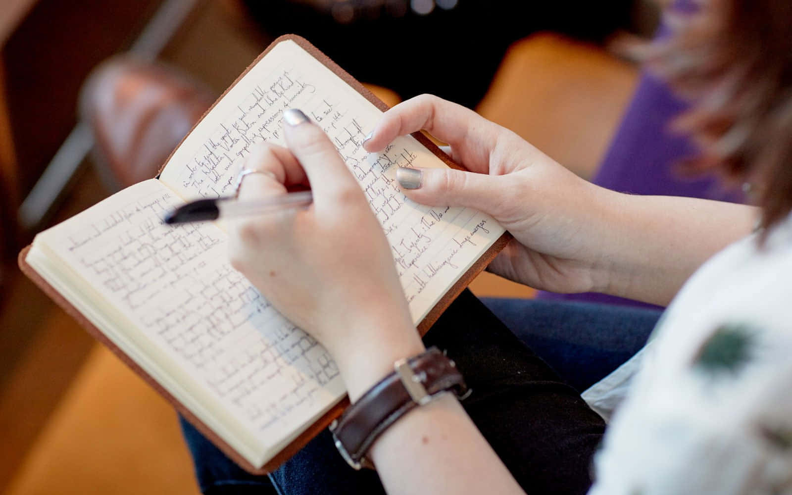 notes 桌布 壁紙 — 特寫鏡頭：雙手在皮革日記本上書寫，塗有銀色指甲油，戴著棕色皮革手錶。